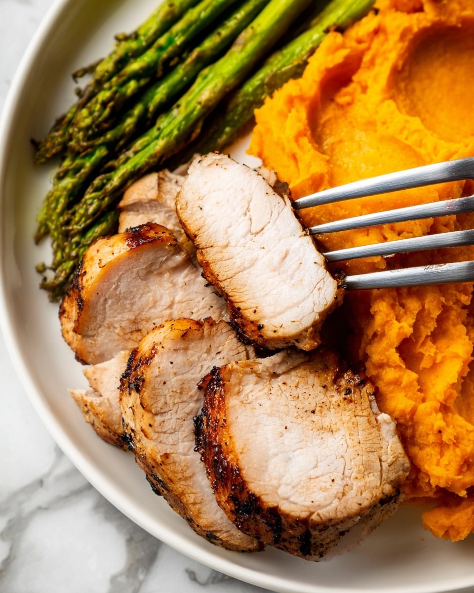 The image shows a white plate with three main layers of food. The top layer features several slices of grilled cooked meat with a light brown outside and a tender, light pink inside. One slice is held up by a fork near the center. Below the meat, there is a layer of bright orange mashed sweet potatoes with a smooth yet slightly textured surface. To the left side of the plate, there is a neat bundle of bright green cooked asparagus stalks showing a shiny, slightly wet texture. The plate is set on a white marbled surface. Photo taken with an iphone --ar 4:5 --v 7