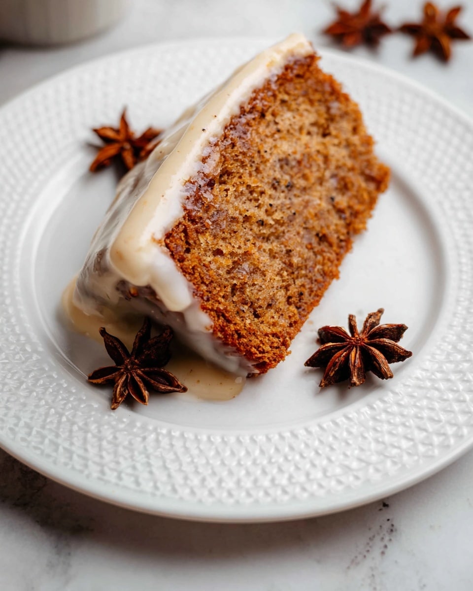 A single slice of brown spiced cake with a rough textured surface and visible small dark specks is on a white plate with a delicate embossed circle pattern along the edge. The cake slice has one layer with a thick white creamy glaze slowly dripping down one side. Three dark brown star anise pods are placed on the plate near the cake slice. The scene is set on a white marbled surface. Photo taken with an iphone --ar 4:5 --v 7