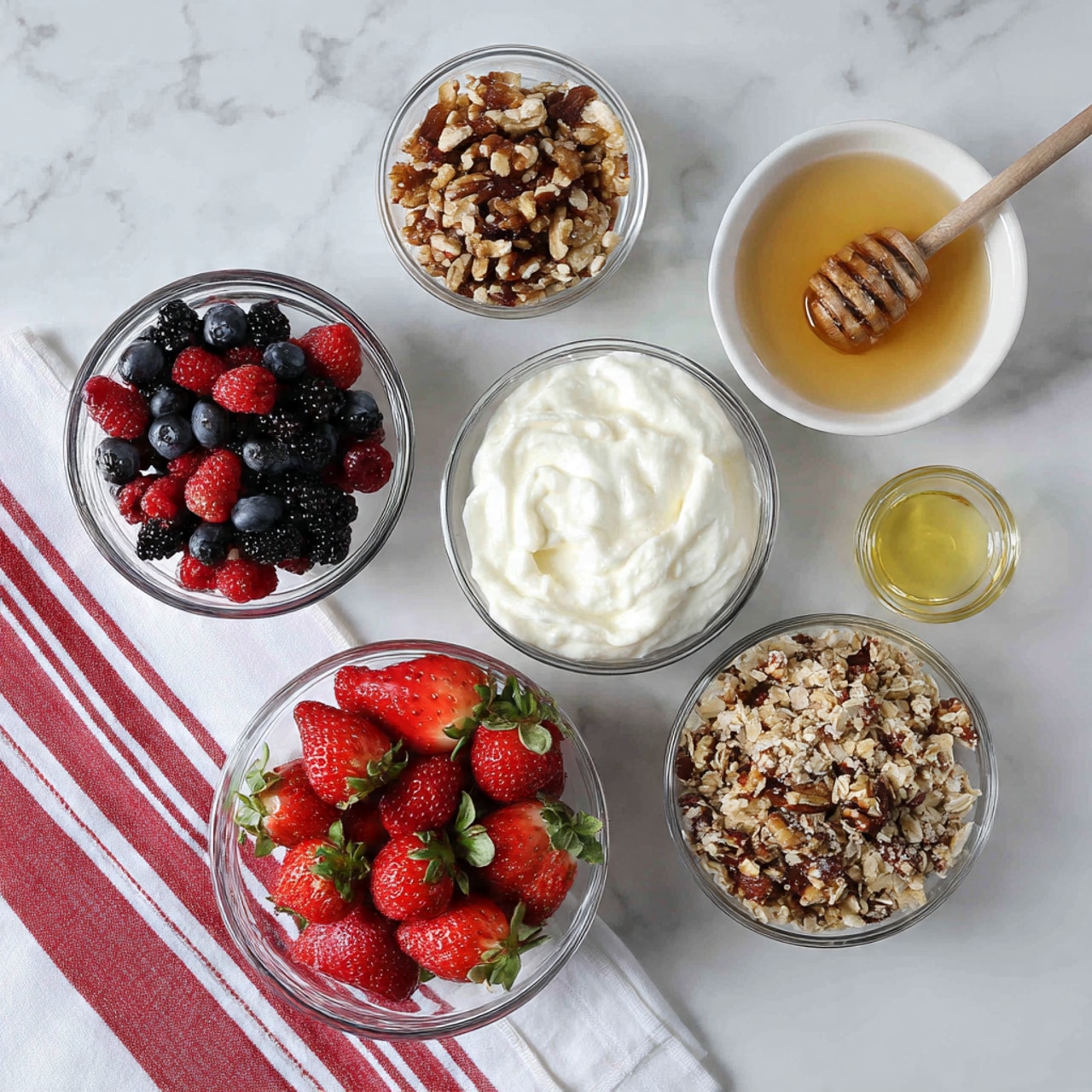 A clear round glass shows a layered parfait with five layers, sitting on a white marbled surface. The bottom layer is creamy white yogurt with some dark blueberries visible inside. On top of this is a layer of mixed berries, including dark blueberries and bright red strawberry slices, showing their juicy texture. Above the berries is a layer of crunchy granola with nuts, oats, and seeds, in warm brown and beige shades. Then there is another thick creamy white yogurt layer, partially covering the berries poking through the yogurt. The top layer is a heap of crunchy granola, with visible whole nuts and oat flakes that are golden brown and beige. Scattered pieces of granola and berries lie on the white marbled surface near the glass, with a silver spoon next to it. photo taken with an iphone --ar 4:5 --v 7