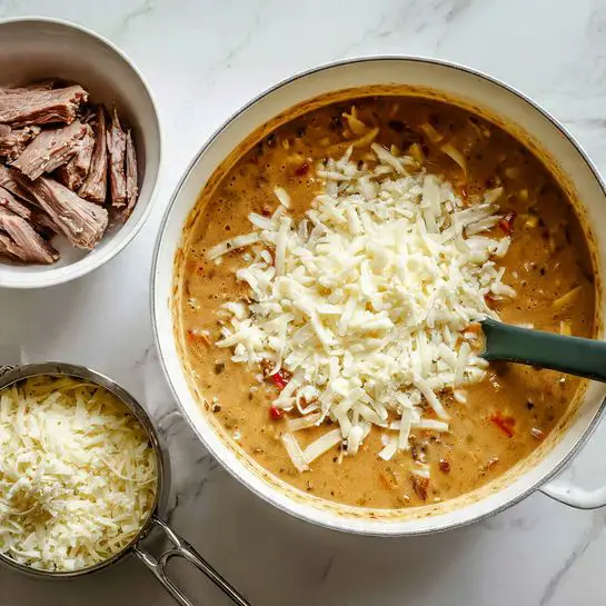 The image shows a white pot with cooked food inside on a white marbled surface. The pot contains a mix of cooked vegetables including sliced mushrooms, red and green bell pepper strips, and finely chopped onions, all lightly browned and mixed together. A silver spoon rests inside the pot, partially covered with the vegetables. Next to the pot is a white bowl filled with cooked pieces of brown meat. The colors in the pot are warm and earthy, with the reds, greens, and browns contrasting against the white pot and bowl. photo taken with an iphone --ar 4:5 --v 7