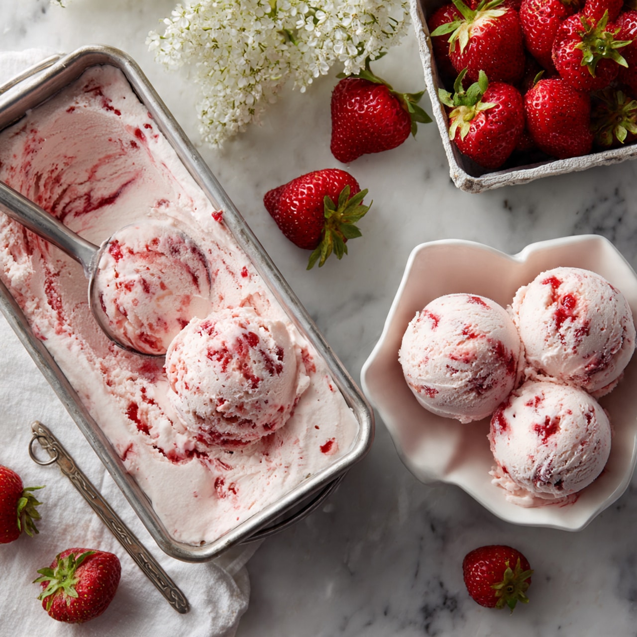 A long metal rectangular container holds creamy, light pink ice cream with swirls of bright red strawberry sauce throughout, creating a marbled effect. Next to the container, a white flower-shaped bowl contains three scoops of the same strawberry ice cream, showing the soft texture with streaks of red sauce on top. Fresh whole strawberries and a white fruit basket filled with strawberries are placed around on a white marbled surface. The photo is taken with an iphone --ar 4:5 --v 7