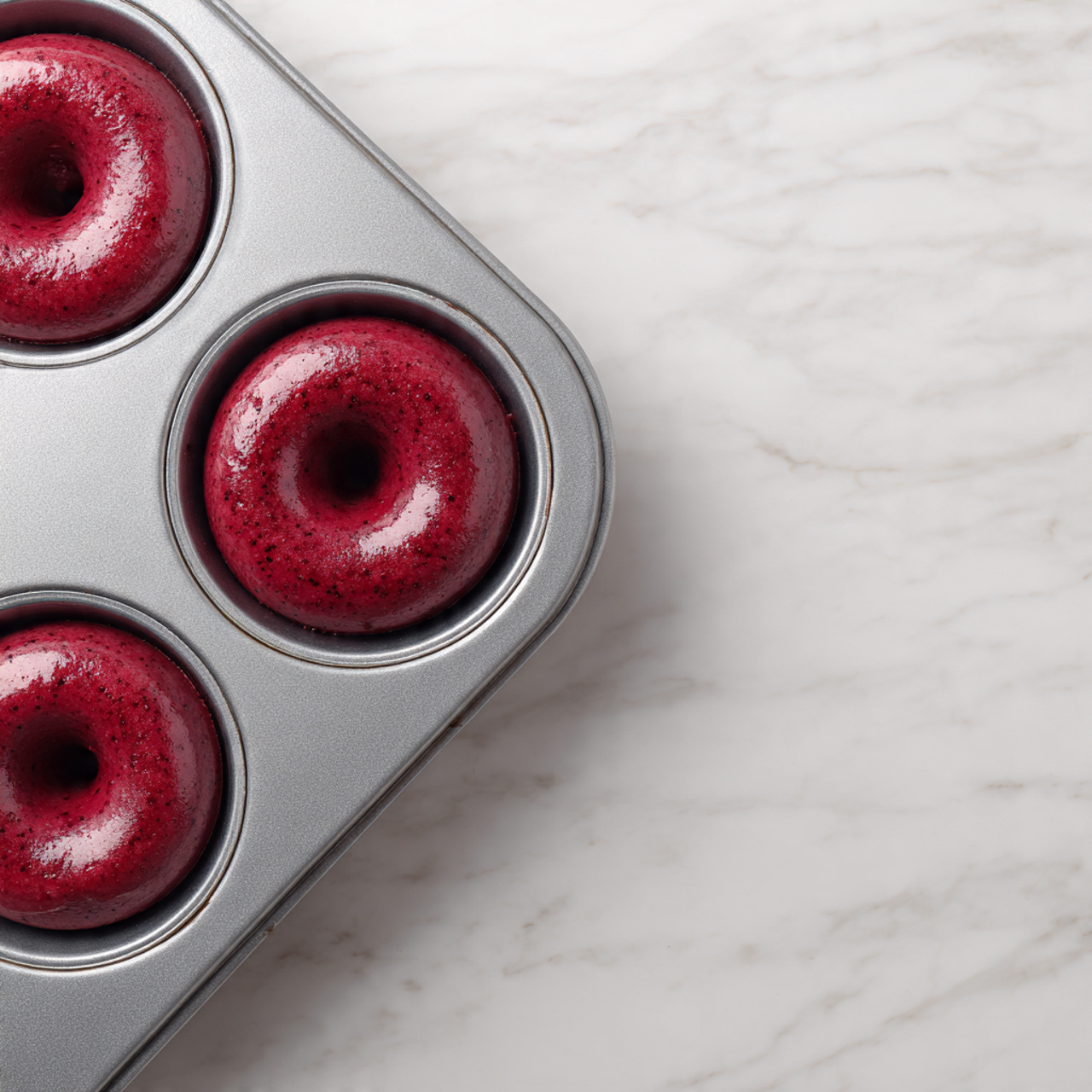 The image shows a stack of three red velvet cakes with thick white frosting layers between them, topped with pink and red sprinkles. The top cake has a bite taken out, revealing a moist, dark red interior. Surrounding the stack are more single-layer cakes with the same white frosting and colorful sprinkles, all placed on a light brown surface. In the background, there is a bottle labeled Lifeway Kefir and a glass container with milk, and the scene is set against a soft peach-colored wall. Photo taken with an iphone --ar 4:5 --v 7