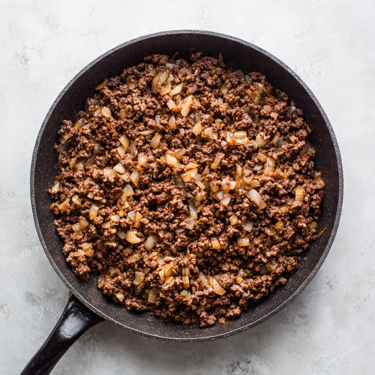 A white rectangular baking dish is filled with a single thick brown layer that looks like cooked ground meat mixed with small pieces of onions in a sauce. On top of this layer, there are nine evenly spaced pale yellow square slices of butter arranged in three rows and three columns. The dish is placed on a surface with a white marbled texture. photo taken with an iphone --ar 4:5 --v 7