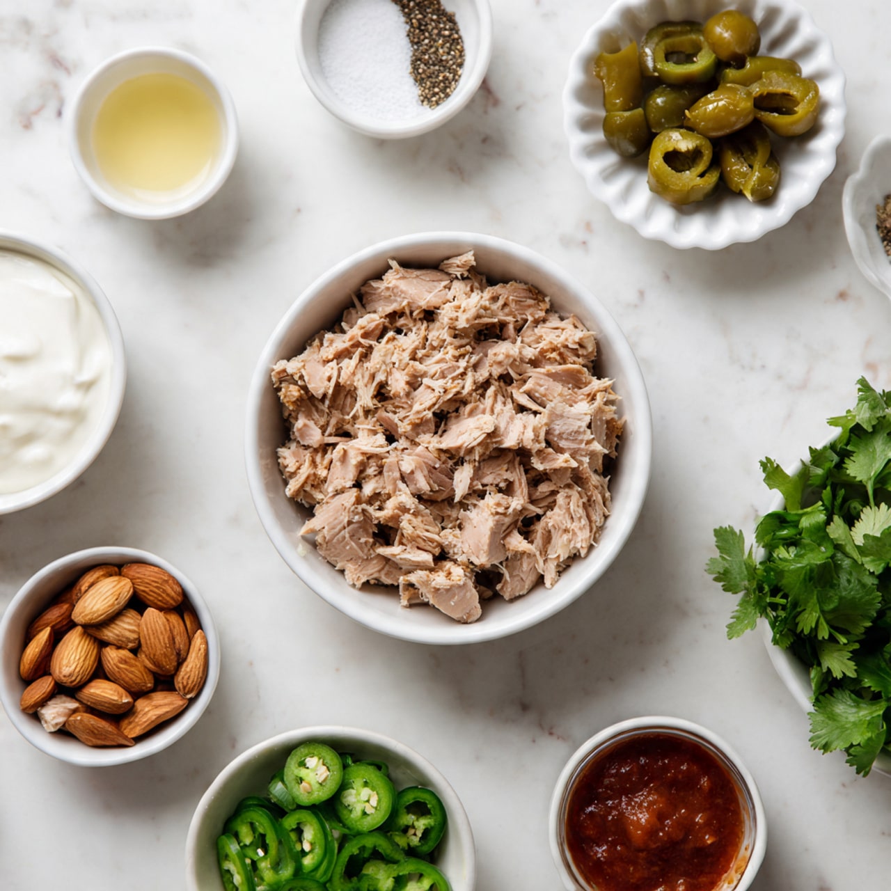 Three bright green lettuce cups sit on a white metal tray placed on a white marbled surface. Each lettuce cup holds a creamy, light orange mixture with visible small celery and herb pieces. The top of the mixture is sprinkled with black and white sesame seeds and chopped almonds. Fresh green cilantro leaves are scattered over the mixture, adding a touch of dark green color. Small pieces of green onion are also visible inside the mixture and around the tray. The scene looks fresh and healthy, with a slight warmth from the light. Photo taken with an iphone --ar 4:5 --v 7