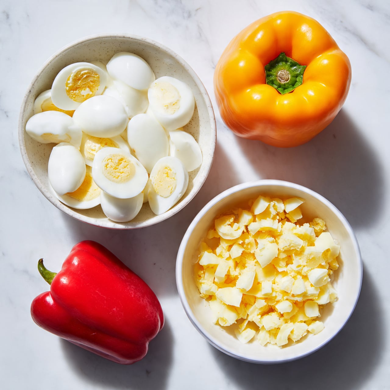 The image shows two white bowls on a white marbled surface. The larger bowl is filled with white egg whites sliced in half, some with small spots of yellow. The smaller bowl contains yellow egg yolks broken into pieces. Around the bowls, there are two whole bell peppers—one yellow and one red—placed near a white cloth with red stripes. To the top right, there is a small Christmas decoration made of a white snowflake, red berries, green leaves, and silver and white baubles. Photo taken with an iphone --ar 4:5 --v 7