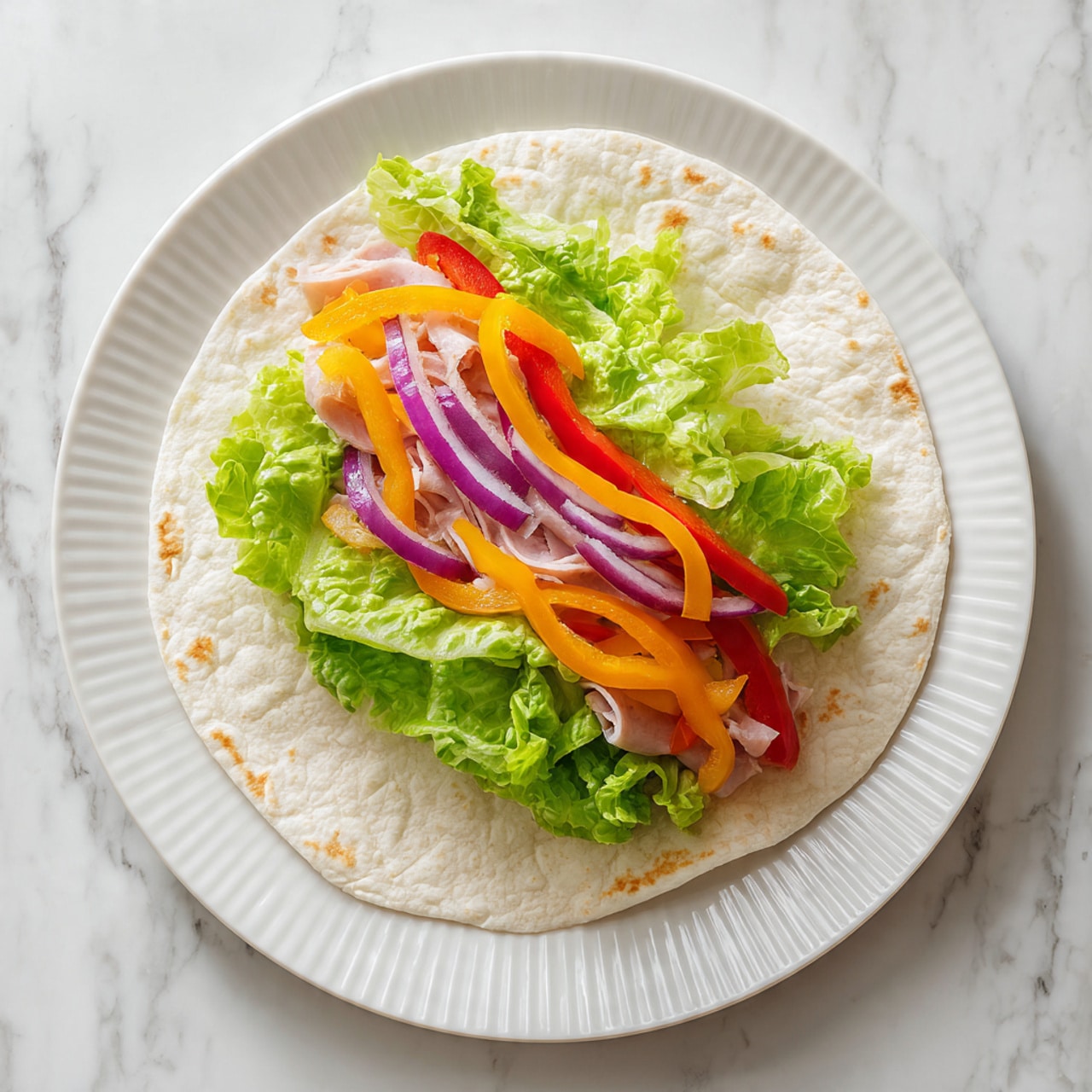 A single flat round tortilla lies open on a white, ridged plate against a white marbled surface. From bottom to top, the first layer is light beige tortilla with a soft texture, followed by thin slices of light pink deli meat spread evenly in an overlapping manner. Above that, there are thin strips of orange and red bell peppers along with thin rings of purple onion. The top layer is made of several large, crisp, and bright light green lettuce leaves loosely stacked in the center. photo taken with an iphone --ar 4:5 --v 7