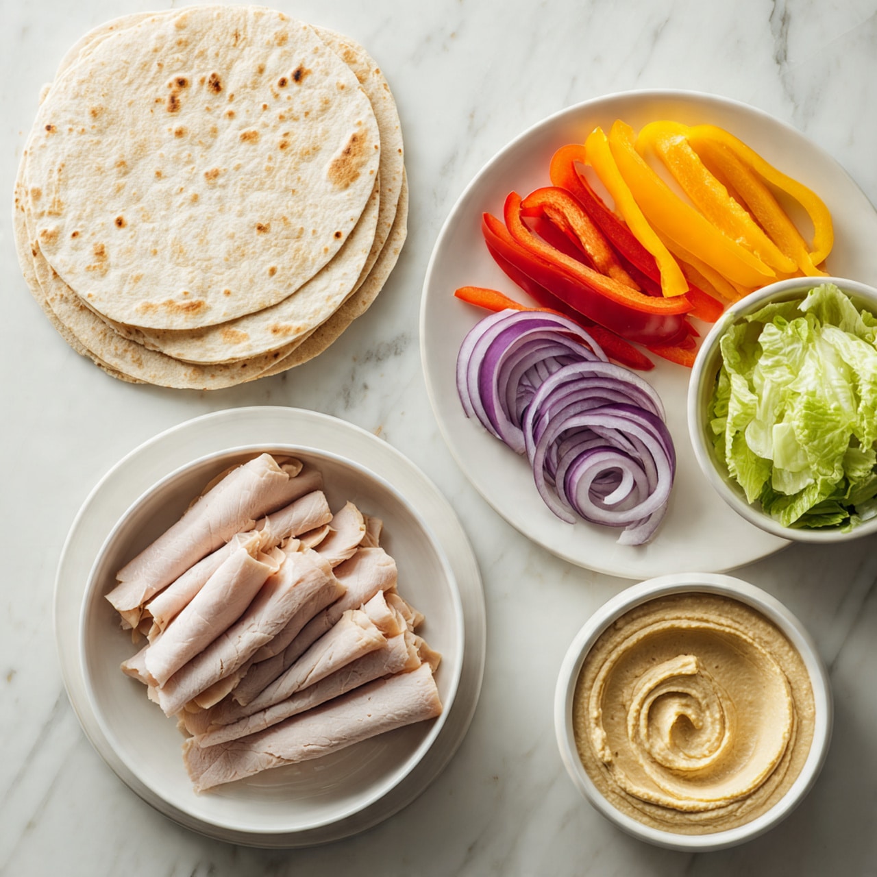 A stack of three round, light tan tortillas with soft texture sits at the top left on a white marbled surface. Below and to the left is a white bowl filled with folded slices of light pink turkey meat with a thin darker edge. To the right of the bowl is another white plate holding fresh sliced vegetables arranged in separate lines: thin purple onion slices, red bell pepper strips, orange bell pepper strips, and yellow bell pepper strips. Above the turkey bowl is a small white bowl full of light green lettuce leaves. At the bottom right is a small white bowl filled with creamy light tan hummus, showing a swirled texture on the surface. photo taken with an iphone --ar 4:5 --v 7
