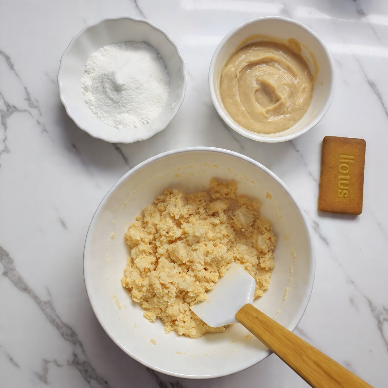 A close-up view of multiple yellow cupcakes each with three layers: the bottom layer is a soft yellow cake, the middle layer is a thick swirl of light brown creamy frosting, and the top layer is a drizzle of darker caramel-colored sauce. Each cupcake is topped with a rectangular brown cookie placed at an angle on the frosting. The cupcakes are arranged on a white marbled textured surface, with some cupcakes partially visible in the background. The lighting is bright and natural, highlighting the smooth texture of the frosting and the crisp edges of the cookies. Photo taken with an iphone --ar 4:5 --v 7