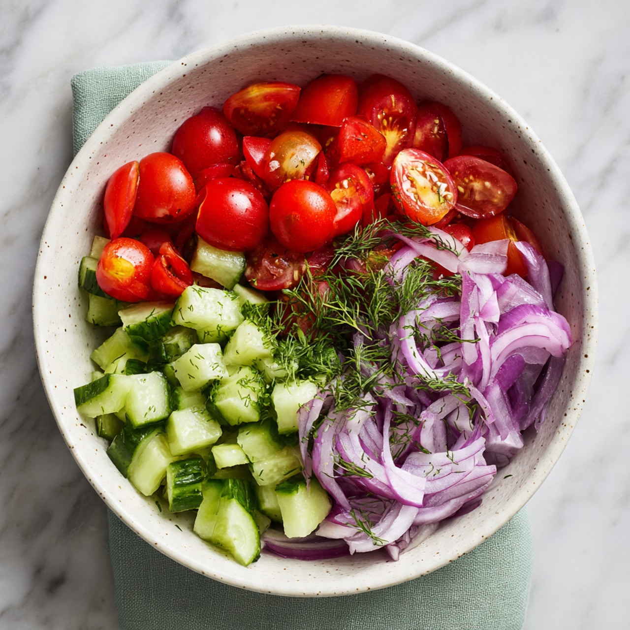 A white pan with a golden handle filled with a single layer of chickpeas coated in a rich dark orange-red oil and spices, some oil pooling at the bottom, giving a shiny texture to the chickpeas. The pan sits on a white marbled surface with fresh green dill sprigs scattered around and a folded olive green cloth partly visible on the left side. The lighting highlights the glossy spices on the chickpeas, creating a warm, appetizing look. photo taken with an iphone --ar 4:5 --v 7