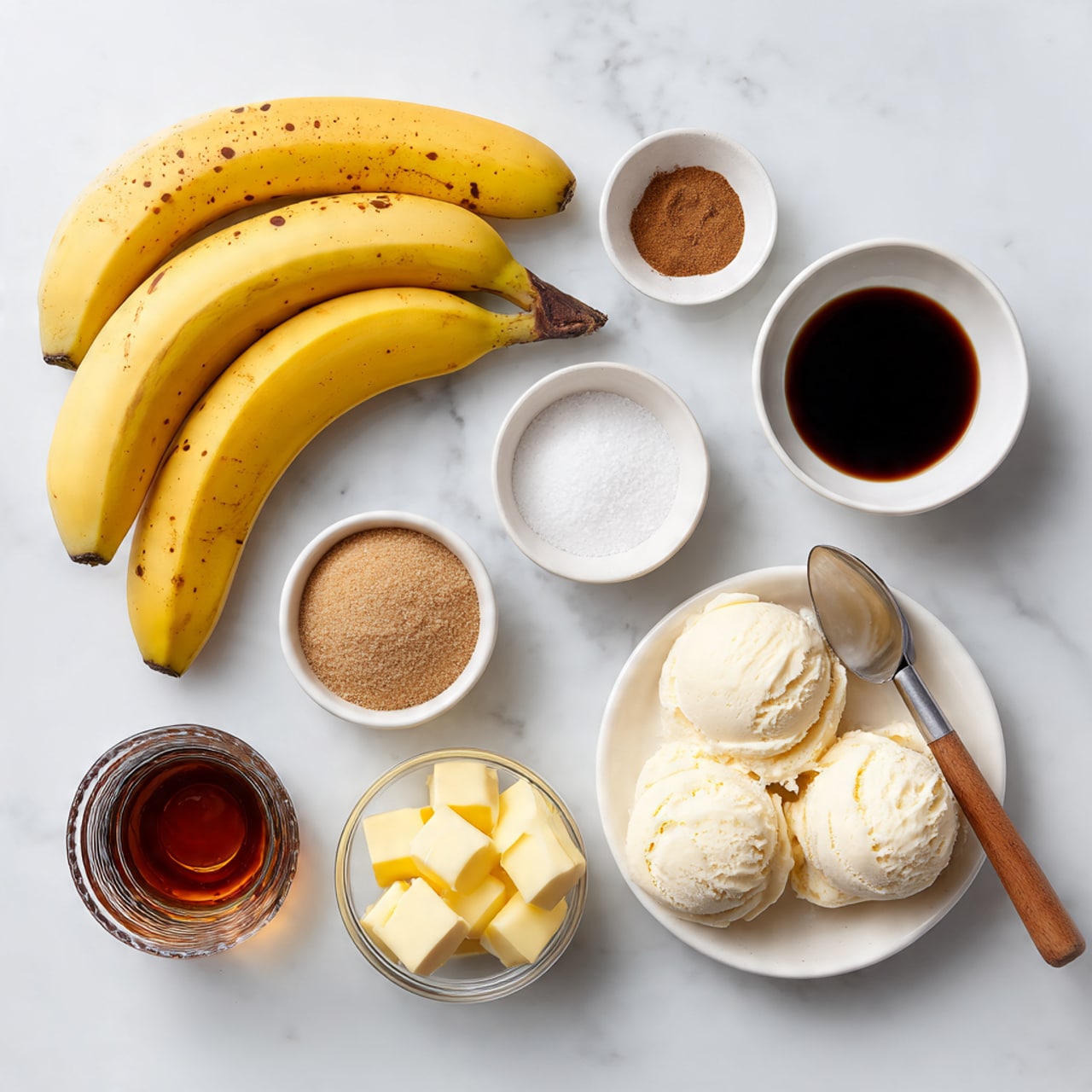 The image shows a flat lay of several ingredients on a white marbled surface. At the top left, there are three yellow bananas with small brown spots. To the right of the bananas is a small white bowl filled with dark liquid labeled vanilla extract. Below the bananas, there is a white bowl filled with light brown coconut sugar. Close to the center, a small round dish contains white salt, and next to it, a white bowl holds a small amount of cinnamon powder. Further down, on the right side, a white plate holds two scoops of vanilla ice cream with an ice cream scoop resting on the plate, the scoop having a wooden handle. In the bottom left, a clear glass has dark rum inside. Next to the glass, a white bowl contains yellow cubes of unsalted butter. All items are neatly arranged and clearly visible. Photo taken with an iphone --ar 4:5 --v 7