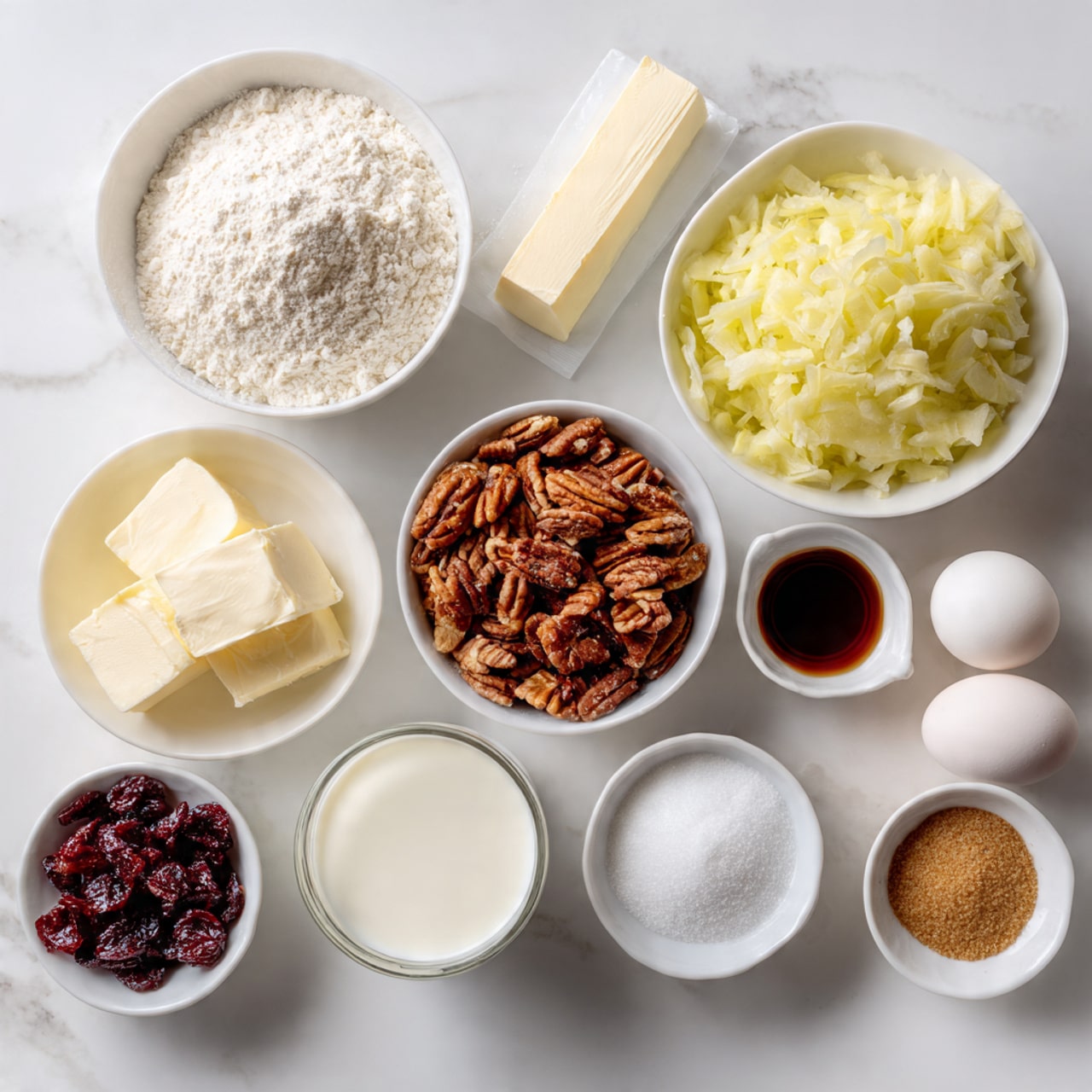 A top view of 10 white bowls and small containers arranged in a loose circle on a white marbled surface. One large bowl holds white flour with a soft texture and light mounded top. Another large bowl contains shredded yellow apple pieces with a moist and fibrous look. A medium white bowl is filled with roughly chopped brown pecan nuts, showing irregular chunky pieces. Next to it, a white bowl holds dark red dried cranberries with a wrinkled texture. A smaller white bowl contains light brown soft-packed brown sugar, smooth on top. Another small bowl contains fine white granulated sugar. There is a very small white bowl with ground cinnamon and white powder placed side by side. A small clear glass holds white milk, a white stick of butter wrapped in paper sits near two white eggs, and a tiny white bowl with dark liquid vanilla extract completes the setup. Photo taken with an iphone --ar 4:5 --v 7