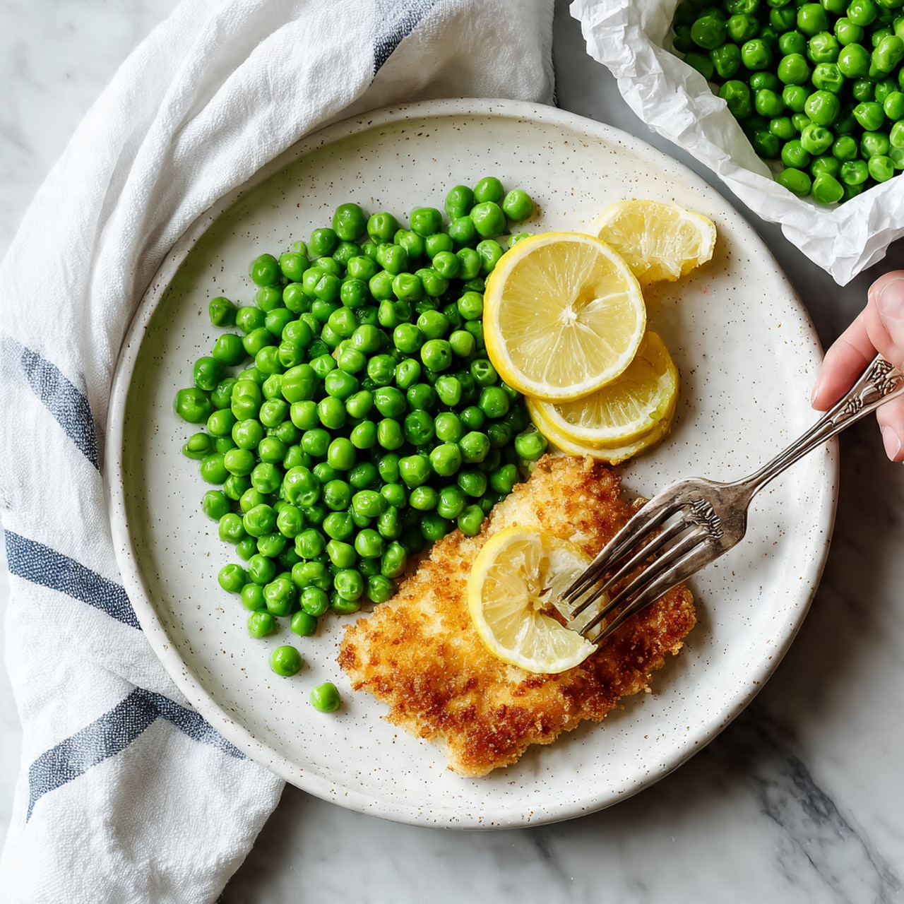 A top view of several ingredients arranged neatly on a white marbled surface. In the center top is a white plate holding two raw cod fillets, pale and smooth. To the right is a small jar filled with bright green chopped parsley. Below that jar are three small white bowls: one with fine grated parmesan cheese, one with a mix of salt and black pepper, and one with three thin lemon slices arranged in a fan shape. On the left side below the plate is a black measuring cup filled with white panko breadcrumbs with a rough texture. Next to it are four small white bowls lined vertically with pale yellow butter, a dollop of light brown mustard, golden olive oil, and lemon slices. Everything is arranged neatly and clearly, all on a white marbled surface. photo taken with an iphone --ar 4:5 --v 7