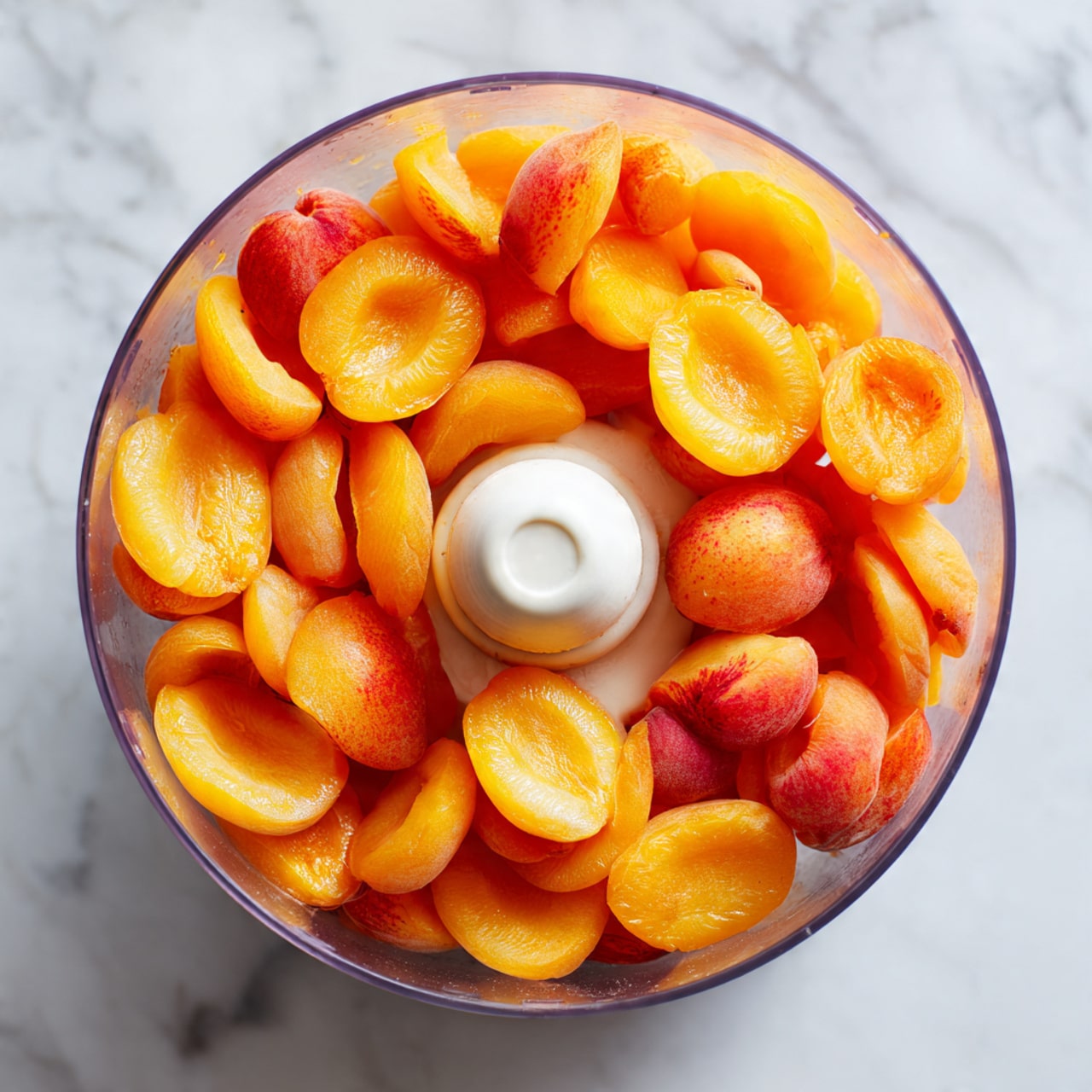 The image shows a round springform pan filled with pale beige batter mixed with scattered light brown almond slices. There are eight bright orange apricot halves evenly placed on top of the batter, forming a circular pattern with one in the center and seven around it near the edge. The pan has a dark metal rim and sits on a white marbled textured surface. Photo taken with an iphone --ar 4:5 --v 7
