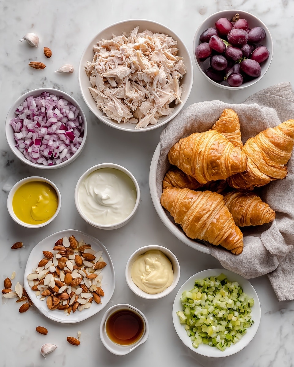 The image shows a white marbled surface with various ingredients for a chicken salad croissant. On the right, there is a white bowl lined with cloth holding five flaky, golden brown croissants. Above this, a wide shallow bowl contains torn, cooked chicken pieces that are light brown and white in color. To the left of the chicken, there is a small bowl of finely chopped red and white onion showing a mix of purples and whites. Below the onion is a small bowl of yellow Dijon mustard next to a bowl of small pale green chopped celery. Below these, there are two small bowls of creamy white substances, one labeled sour cream and the other labeled mayo. To the left of those bowls, there is a white plate with sliced almonds scattered around. Above the almonds plate is a small white bowl filled with halved dark purple grapes. A very small cup with light brown vinegar sits between the grapes and onion. The whole set is arranged neatly on the white marbled surface in a clean and bright setting photo taken with an iphone --ar 4:5 --v 7