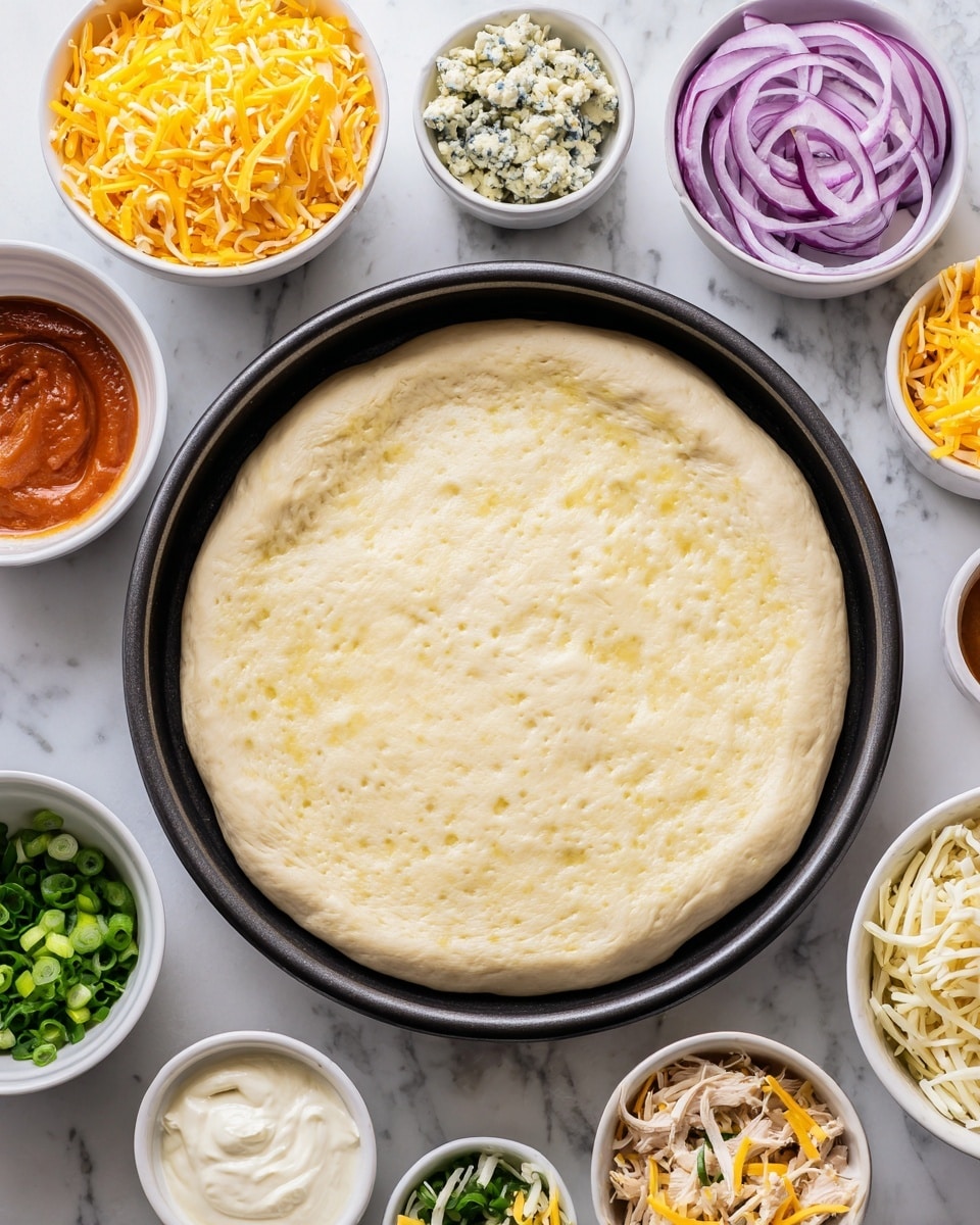 A round pizza crust sits in a black pan at the center on a white marbled surface. Surrounding it are small white bowls with ingredients arranged neatly: shredded cheddar cheese in a bright orange-yellow tone, crumbled blue cheese with a mix of white and blue-green spots, shredded white mozzarella, thinly sliced red onion with purple and white layers, creamy ranch sauce speckled with herbs, chopped green onions in vibrant green, shredded cooked chicken in light beige, and a small bowl of orange-red buffalo sauce. Each ingredient is clearly separated, ready to be added to the pizza. photo taken with an iphone --ar 4:5 --v 7