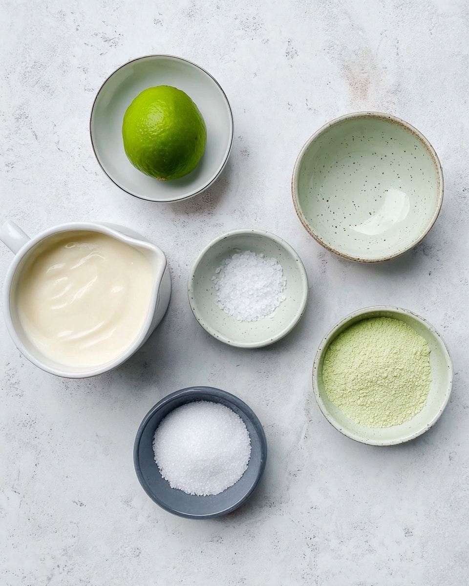 The image shows seven small white bowls and a pitcher arranged on a white marbled surface. The top left bowl holds one whole bright green lime with a smooth texture. Below it, a bowl contains smooth off-white cream. At the bottom left, a white pitcher holds fresh milk. The top middle bowl is empty with a light grey inside and specks. Below it, there is a small bowl filled with white coarse salt. At the bottom middle, there is an empty small grey bowl. The top right large bowl contains light green fine powder with a soft texture. All bowls are viewed from above, and the setting is clean and minimalistic. Photo taken with an iphone --ar 4:5 --v 7