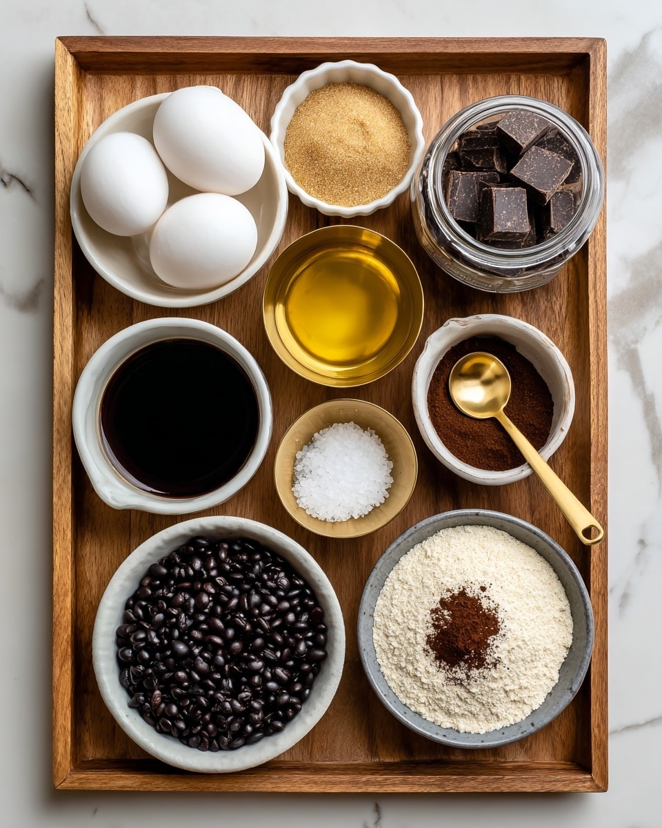 The image shows a wooden tray with various baking ingredients neatly arranged on it. At the top left, there's a white bowl with two white eggs. Below it, a small white bowl filled with golden avocado oil. In the center top, a golden measuring cup full of light brown sugar. To the right of it, a small glass jar with dark vanilla extract. Below that, a golden measuring cup filled with semi-sweet chocolate chunks. In the middle of the tray, a white bowl with dark maple syrup. Below it, a small golden measuring spoon with sea salt. At the bottom right, a small white bowl with dark brown cocoa powder. Bottom center holds a white bowl full of pale almond flour. Finally, bottom left has a gray bowl filled with dark black beans. The surface under the tray is a white marble texture photo taken with an iphone --ar 4:5 --v 7