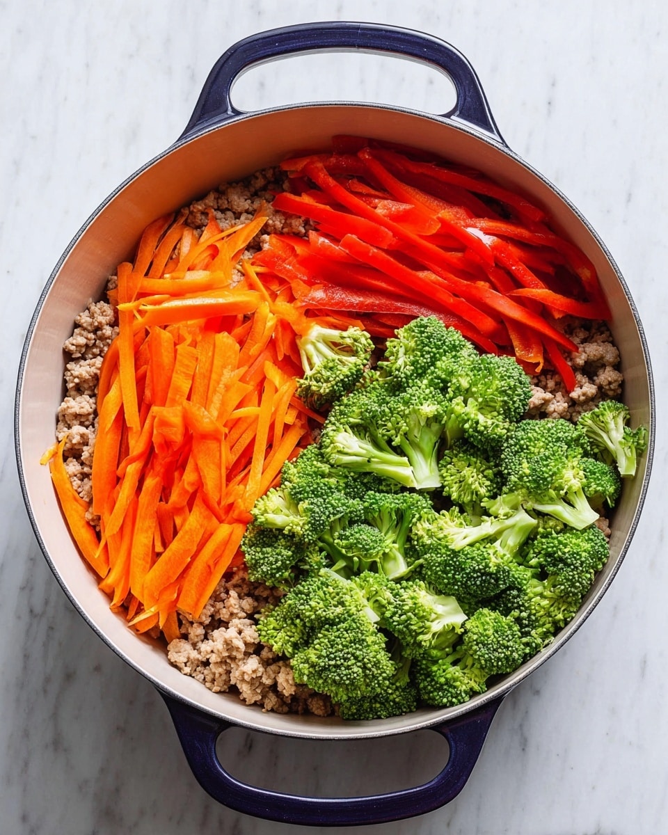 A white round pot with dark blue handles sits on a white marbled surface, filled with four visual layers. The bottom layer is pale beige cooked ground meat covering the base. On top, arranged in three sections, are thin red strips of bell pepper on the left, bright orange thin strips of carrot in the bottom center, and fresh green broccoli florets on the right. Each vegetable layer shows a rough and natural texture with varying thickness. The colors are bright and distinct, making the dish vibrant and fresh photo taken with an iphone --ar 4:5 --v 7