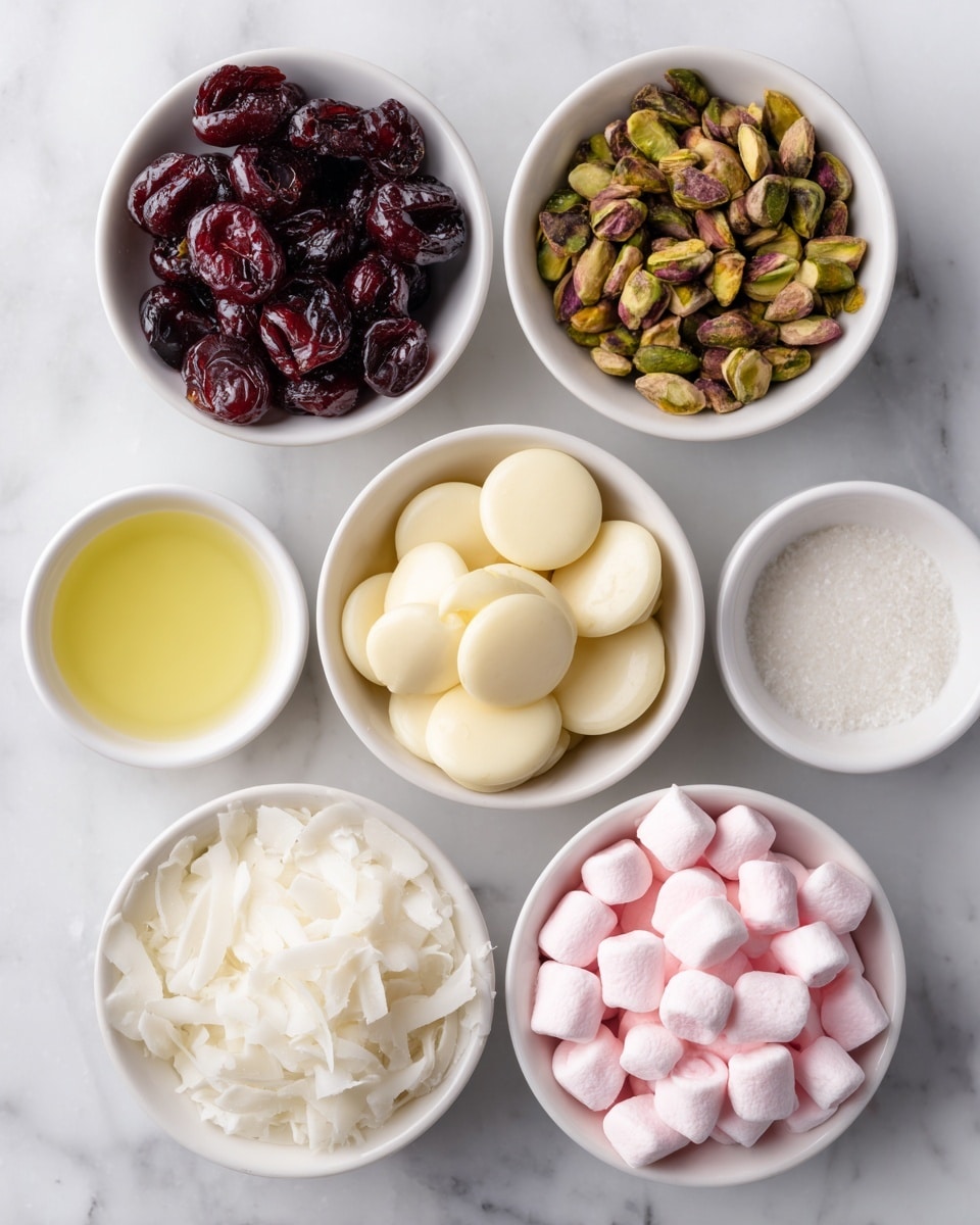 The image shows six small white bowls on a white marbled surface, each filled with different ingredients. At the top left, there is a bowl filled with dark red glace cherries that have a shiny and wet texture. Next to it on the top right is a bowl with green pistachios that have a rough and crunchy texture. In the center is a bowl filled with round, pale yellow white chocolate disks, smooth and creamy in look. Below the cherries is a small bowl containing clear light yellow oil. Next to the oil is another bowl filled with white shredded coconut, soft and fluffy in appearance. At the bottom right, a bowl contains pink and white marshmallows, soft and puffy, spread unevenly in the dish. All bowls are arranged neatly on the white marbled surface. photo taken with an iphone --ar 4:5 --v 7