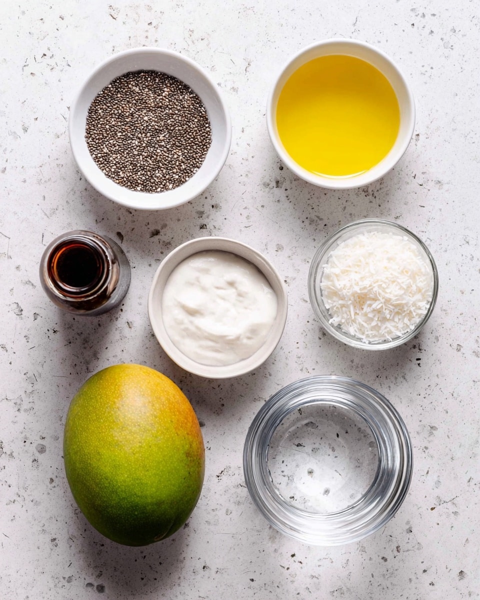 The image shows seven ingredients arranged neatly on a white marbled surface. Starting from the top left, there is a white bowl filled with many small, dark chia seeds with a rough texture. Next to it on the right, there is a white bowl filled with bright yellow liquid, likely oil, which has a smooth surface. To the right of that, a clear glass holds a transparent liquid, probably water. Below this, slightly to the left, is a whole mango that is green with yellow patches and a shiny, smooth skin. Below the mango, there is a clear glass bowl with a thick off-white creamy substance inside. To the left of the creamy bowl, a small dark brown bottle with a wide mouth is placed. Above this bottle is another white bowl containing fine white shredded flakes, probably coconut, which have a soft texture. All items are spaced evenly and give a clean, fresh look. photo taken with an iphone --ar 4:5 --v 7