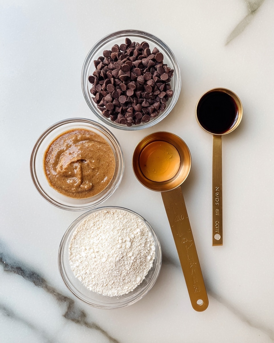 The image shows five small containers on a white marbled surface, each holding a different ingredient. At the top left is a clear glass bowl full of small, dark brown chocolate chips, next to it on the right is another clear glass bowl filled with light brown almond butter. Below the chocolate chips is a small clear glass bowl with a light brown liquid, possibly vanilla extract. Next to it on the right is a gold measuring spoon with a dark liquid, about a quarter cup in size, and below that, a gold measuring cup filled with white fine almond flour, about one cup. The containers are neatly arranged and evenly spaced. Photo taken with an iphone --ar 4:5 --v 7