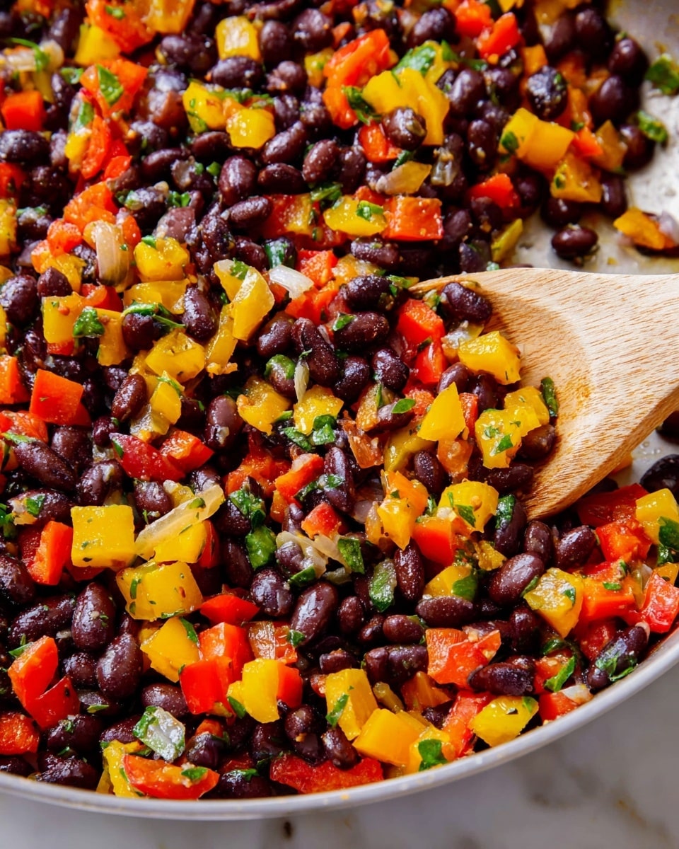 The image shows a close-up of a colorful mix of chopped vegetables and black beans. The dish has three main layers: large black beans scattered evenly, small diced red and yellow bell peppers adding bright pops of color, and tiny bits of green herbs sprinkled throughout. The texture looks soft and a bit shiny as if cooked or sautéed, with small specks of seasoning visible on some pieces. A wooden spoon is in the mix, showing part of its light tan handle and rounded edge. The whole dish is on a white marbled surface. photo taken with an iphone --ar 4:5 --v 7