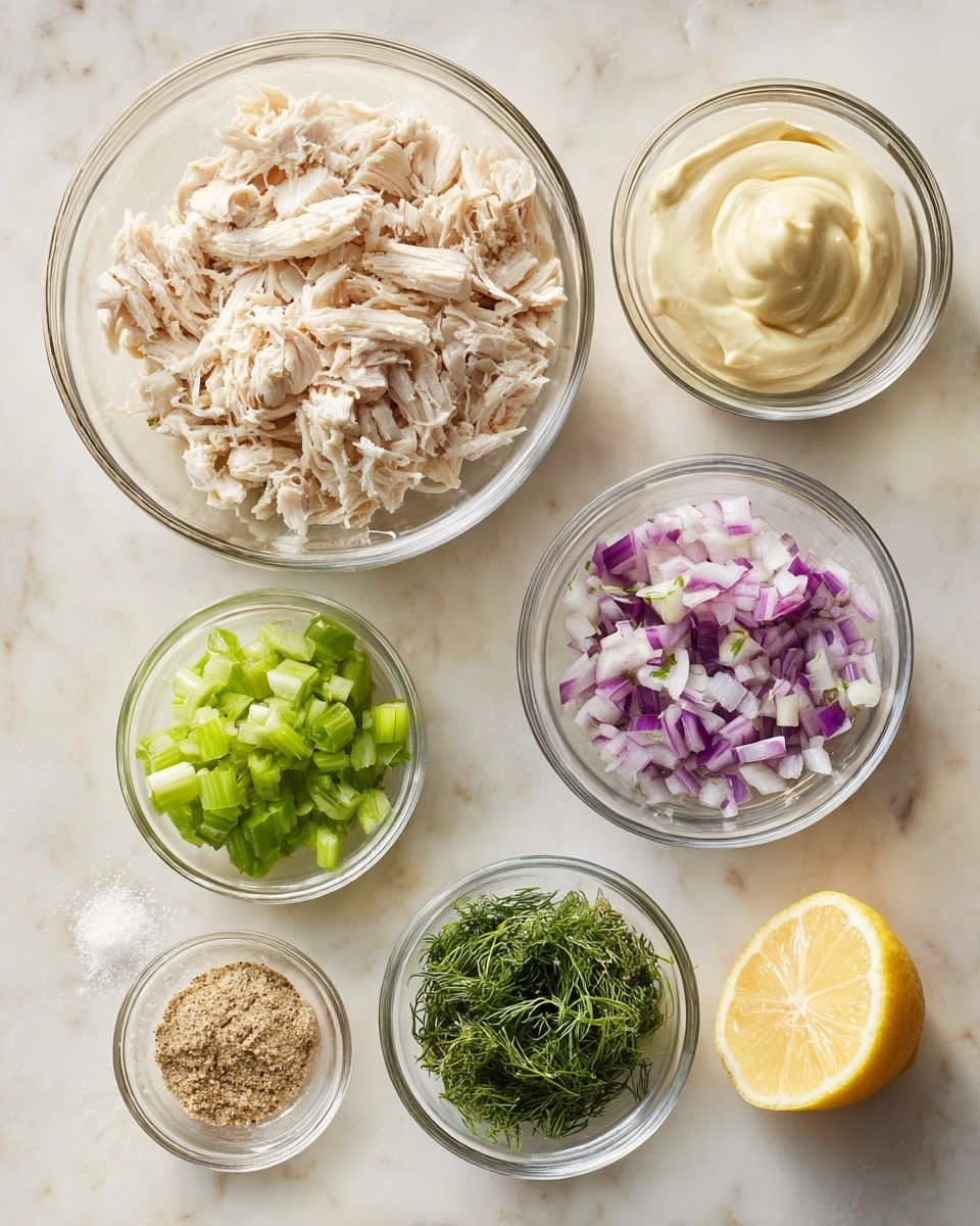 A top-down view shows seven small clear glass bowls arranged on a white marbled surface, each containing different ingredients. The largest bowl at the top left is filled with shredded pale beige chicken. To the right of it is a medium bowl with smooth, creamy pale yellow mayo. Below the chicken bowl is a small bowl with bright green diced celery. Next to it, in the center, is a smaller bowl filled with fine dark green dill leaves. To the right, a small bowl contains finely chopped pieces of purple and white red onion. Below these, on the left is a tiny bowl with coarse light brown garlic powder, and next to it, a small bowl holding coarse white salt and black pepper mixed together. On the bottom right corner sits a halved yellow lemon showing the juicy inside. The scene looks clean with soft natural light photo taken with an iphone --ar 4:5 --v 7