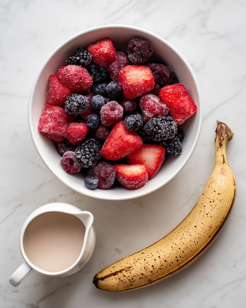 A white bowl filled with frozen mixed berries, including red strawberries, dark purple blackberries, and blueberries, sits on a white marbled surface at the top center. Below the bowl, slightly to the right, lies a whole frozen banana with a brown, speckled peel. To the left of the banana, there is a small white pitcher filled with almond milk, with a smooth pale beige liquid inside. The layout is simple and clean, with each item spaced evenly on the white marbled background, photo taken with an iphone --ar 4:5 --v 7