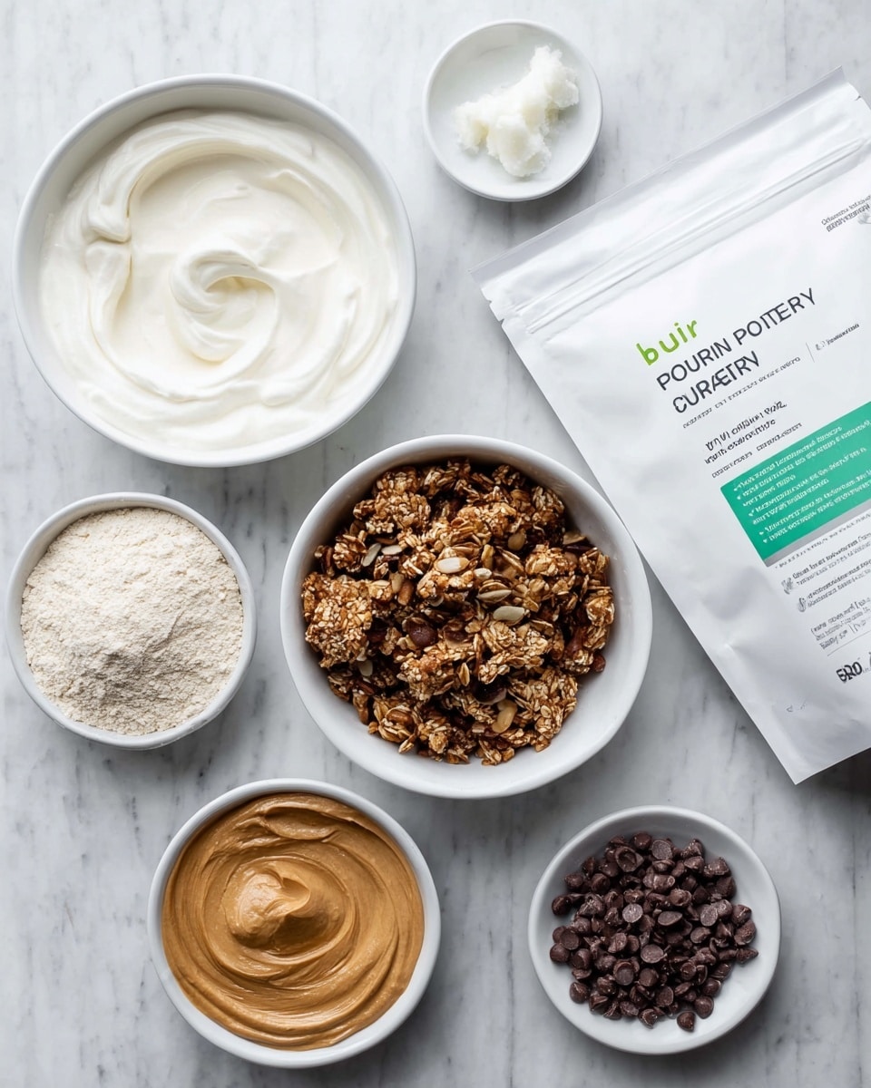 The image shows a white speckled muffin tray with two layers inside each cup. The bottom layer is a rough textured mix of nuts and granola in various shades of brown and beige, filling about one-third of each cup. The top layer is a smooth light beige creamy mixture being scooped into the cups, covering the granola base. A woman's hand holds the scoop filled with the creamy mixture above one of the cups. The tray sits on a white marbled surface. photo taken with an iphone --ar 4:5 --v 7