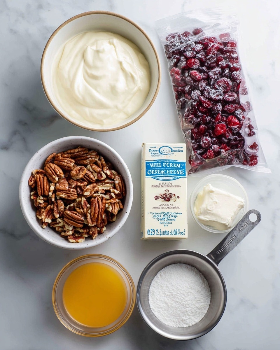 The image shows several baking ingredients arranged on a white marbled surface. In the top left, there is a white bowl with beige edges holding heavy whipping cream, smooth and white. Below it is a rustic white bowl filled with chopped pecans, brown with varied textures. To the right, a colorful bag of dried cranberries stands upright, mostly white with red cranberries pictured. Below the pecans is a rectangular box of cream cheese, white and blue with text. Near the bottom, two clear glass containers hold bright orange liquid labeled orange juice concentrate and light brown liquid labeled vanilla. Finally, a metal measuring cup is filled with fine white powdered sugar. All labels are clear and text is bold. Photo taken with an iphone --ar 4:5 --v 7
