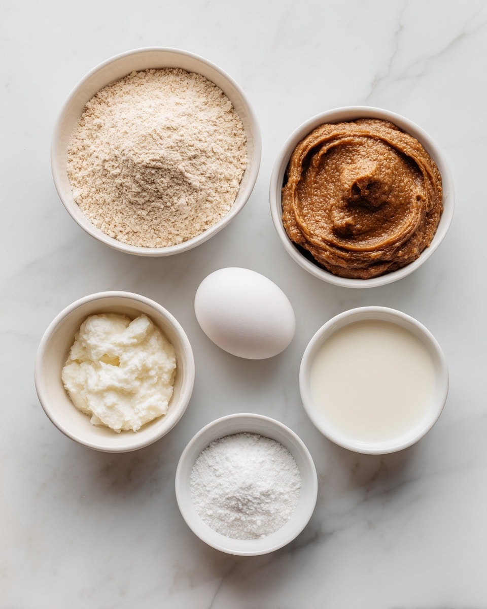 Six small bowls and one egg are arranged on a white marbled surface. The top left bowl holds a light beige oat flour with a powdery texture. Next to it on the right is a small white bowl filled with smooth, creamy white milk. Below the oat flour is a white bowl with a thick, textured brown date paste. To the right of the date paste is a single white egg placed directly on the surface. Below the egg on the right is a small white bowl containing solid white coconut oil. Finally, at the bottom left is a white bowl with fine white baking powder. Each item is neatly spaced and clearly visible. Photo taken with an iphone --ar 4:5 --v 7