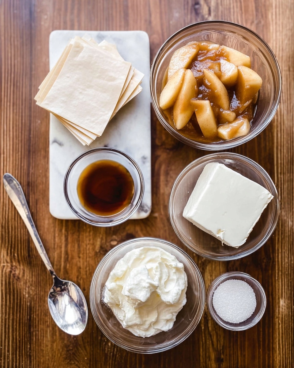 A top view of several clear glass bowls and a spoon placed on a wooden surface. In the center, there is a stack of square, light beige sheets arranged neatly. Above the sheets is a bowl filled with sliced, cooked apple pieces in a thick brown sauce. To the right of the apple bowl is another bowl containing a block of white cream cheese. Below the cream cheese bowl, a smaller bowl holds a white creamy substance, possibly sour cream. Below the square sheets, there is a small bowl with light brown liquid, likely vanilla extract. To the left of the sheets is a small bowl filled with white granulated sugar. A shiny silver spoon lies diagonally across the bottom left of the image, reflecting a woman's hand and part of the room. The whole scene is on a white marbled texture background. photo taken with an iphone --ar 4:5 --v 7