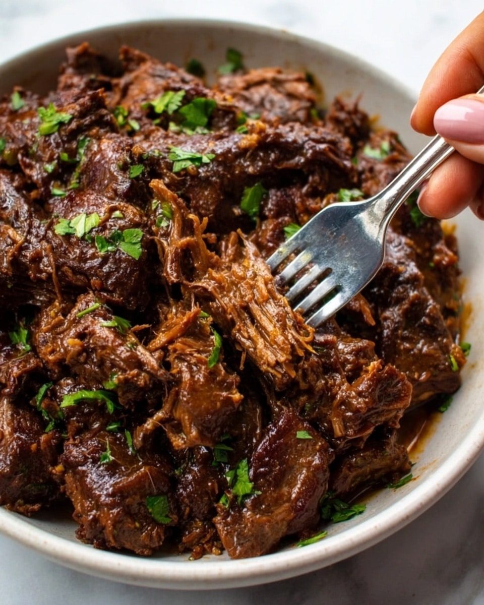 The image shows a close-up of a white bowl filled with shredded dark brown meat covered in a glossy sauce. The meat appears tender and juicy, with pieces varying in size and texture. Small, fresh green parsley leaves are sprinkled on top, adding a pop of color. A woman's hand holds a fork that is picking up some of the meat, pressing into the soft texture. The bowl rests on a white marbled surface. Photo taken with an iphone --ar 4:5 --v 7