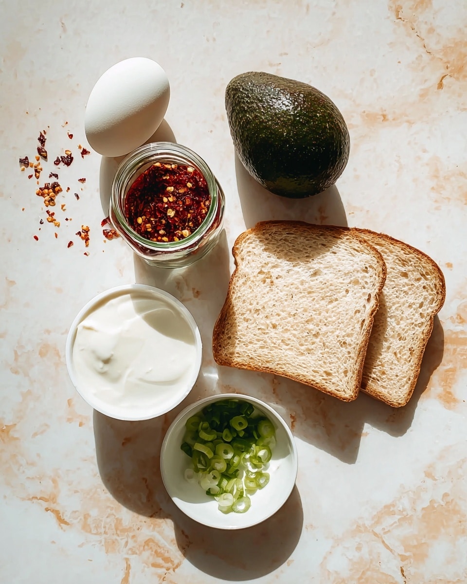 The image shows an overhead view of six food items placed separately on a white marbled surface: a glass jar filled with red chili flakes and seeds with the lid off, a whole dark green avocado with a bumpy texture, a white egg, an open white container of thick white yogurt, a single slice of whole grain bread with a light brown crust and soft texture, and a small white bowl filled with chopped green onions. Shadows cast by the items are visible, adding depth to the composition. photo taken with an iphone --ar 4:5 --v 7