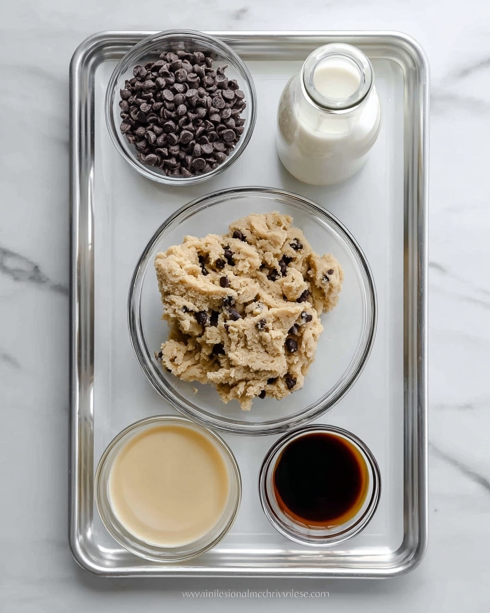 The image shows a large white tray with five bowls and a small bottle arranged on top. At the center, a large clear glass bowl holds a mixture of light tan cookie dough with small dark chocolate chips scattered throughout. Above that, a small clear bowl is filled with only dark chocolate chips. To the right of the chocolate chips, a tall clear bottle contains white milk. Below the dough bowl, a small clear glass bowl has thick creamy condensed milk with light yellow color. Next to it, a tiny clear bowl holds a dark brown liquid, likely vanilla extract. The tray rests on a white marbled surface. photo taken with an iphone --ar 4:5 --v 7