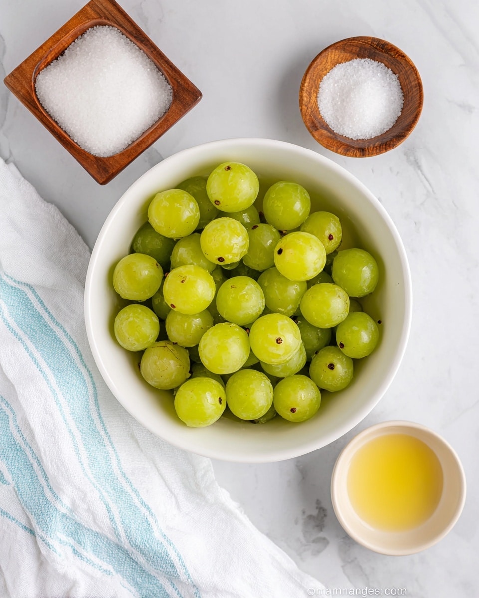 A white bowl filled with bright green grapes sits in the center on a white marbled surface. To the top left, a wooden square bowl holds white granulated sugar, and to the top right, a small round wooden bowl has white salt. At the bottom right, there is a small white bowl with a light yellow liquid, and a blue-and-white striped cloth is draped on the bottom left corner of the surface. photo taken with an iphone --ar 4:5 --v 7