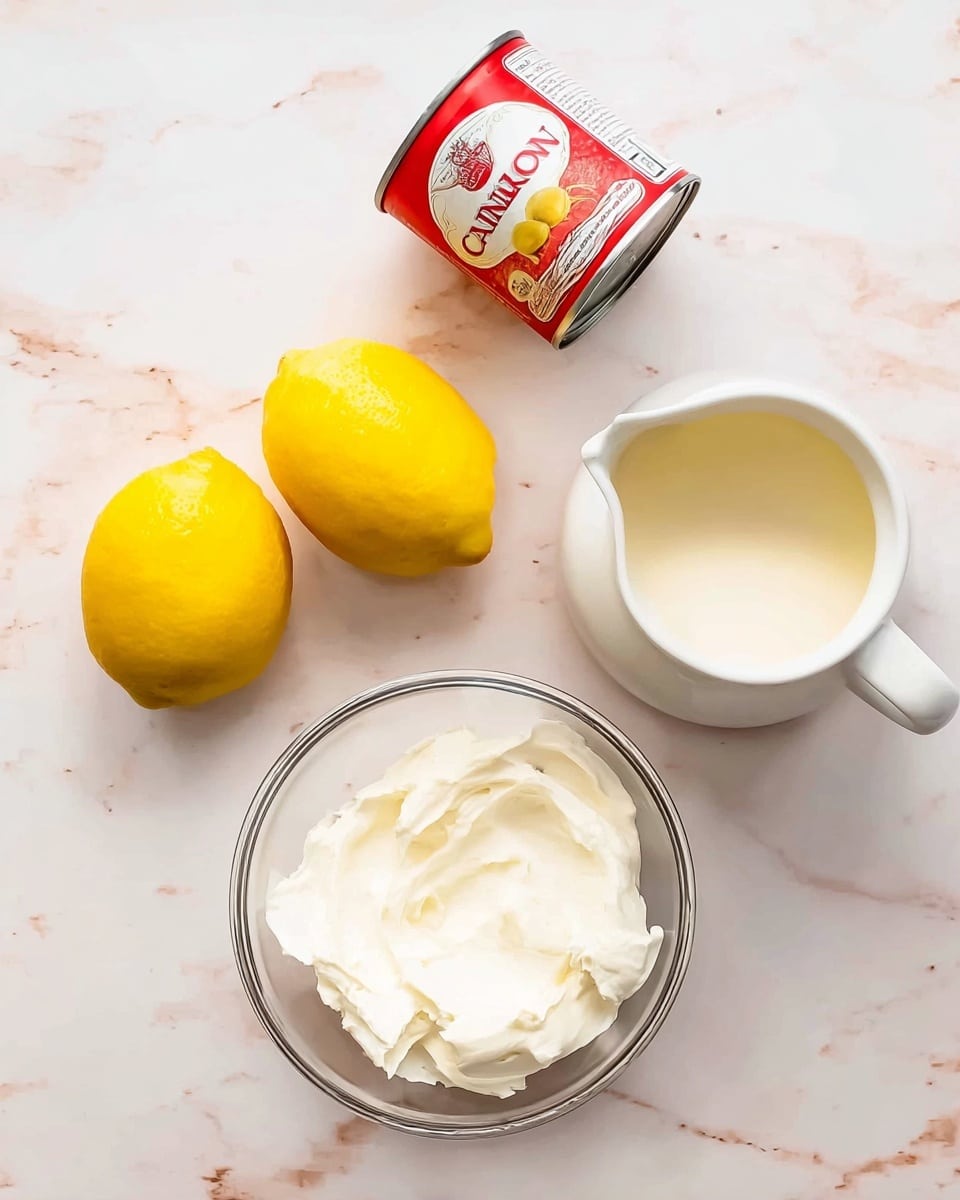 The image shows ingredients for a dessert arranged on a white marbled surface. There are two bright yellow lemons on the left side, next to a red and white can of condensed milk. To the right of the can, there is a white pitcher filled with cream, and below it, a clear glass bowl containing soft white cream or whipped mixture. The colors are soft and natural, with the lemons standing out against the creamy white tones of the other ingredients. Photo taken with an iphone --ar 4:5 --v 7
