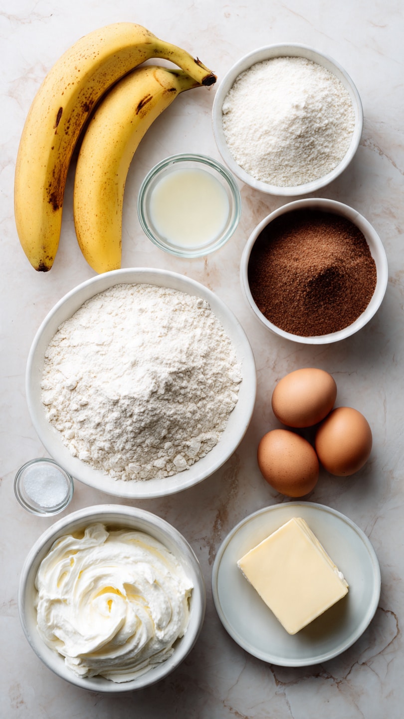 A top view of baking ingredients arranged neatly on a white marbled surface with three ripe yellow bananas with brown spots on the left. In the middle, a white bowl filled with mashed bananas sits below a large white bowl of flour. Above the flour, a white bowl holds white sugar, and next to it, another white bowl contains packed brown sugar. To the right, a small white plate holds two brown eggs, beside a stick of butter in its wrapper and a small white bowl with salt. To the left of the flour, there is a small clear glass bowl with vanilla extract and a large white bowl with whipped cream. photo taken with an iphone --ar 4:5 --v 7