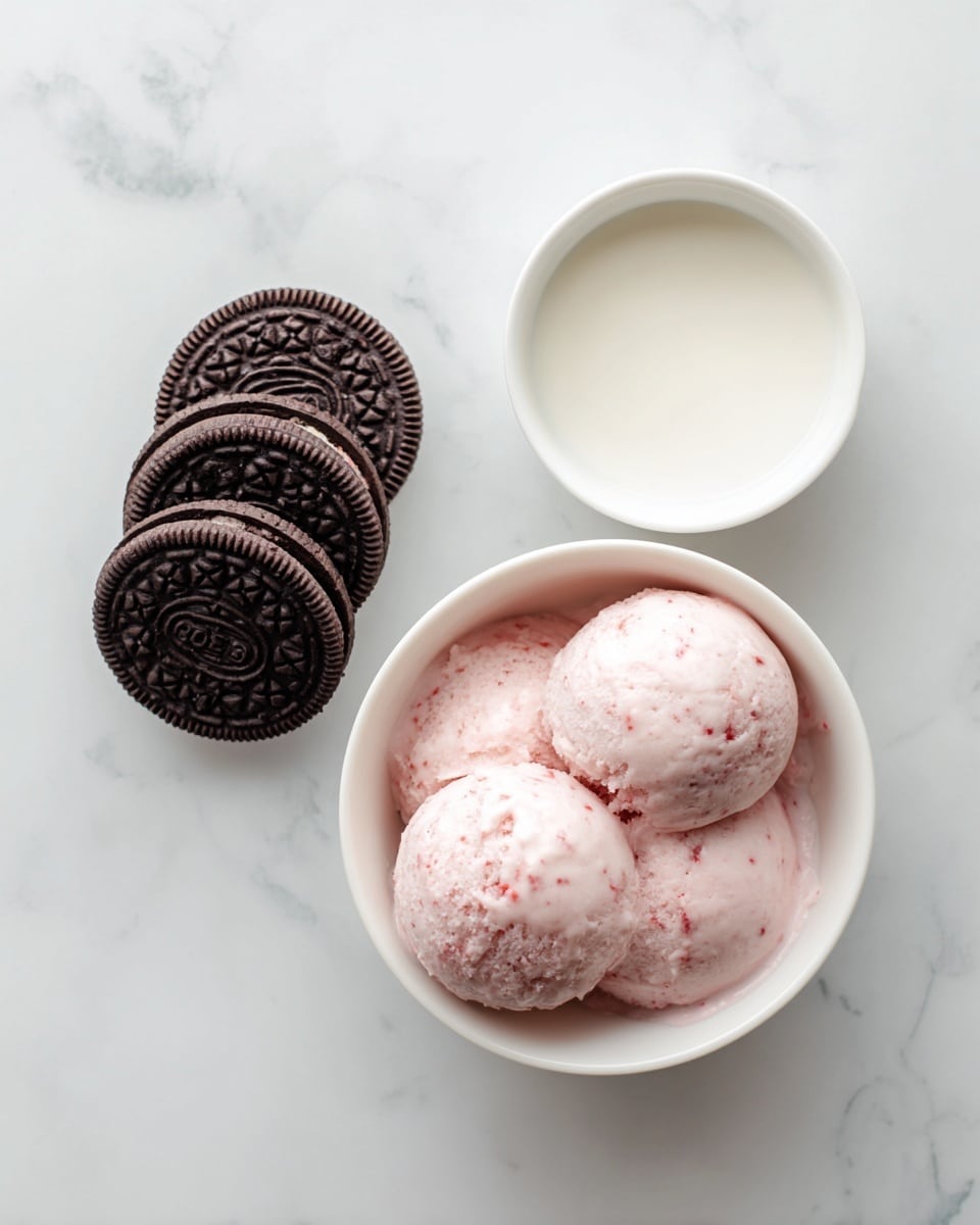 The image shows three simple ingredients on a white marbled surface. On the left, there are four dark brown Oreo cookies stacked slightly overlapping each other. On the right, a small white bowl holds a smooth white liquid, labeled as 1/3 cup of milk. Below these, there is a white bowl filled with one cup of light pink strawberry ice cream, which has a creamy texture with small darker pink spots. The setup is clean, minimal, and brightly lit, with text labels beside each ingredient. Photo taken with an iphone --ar 4:5 --v 7