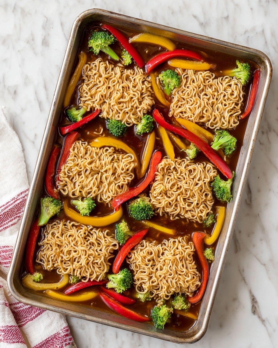 The image shows a metal baking pan filled with five blocks of light brown uncooked ramen noodles evenly spread out. Surrounding the noodles are thin slices of bright red and yellow bell peppers layered in a scattered pattern. Small green broccoli florets are placed all over the pan, adding more color and texture. The entire pan's contents are sitting in a shallow pool of dark brown sauce, giving the ingredients a glossy look. The pan rests on a white marbled surface with a white and red striped cloth peeking in from the bottom left corner. photo taken with an iphone --ar 4:5 --v 7