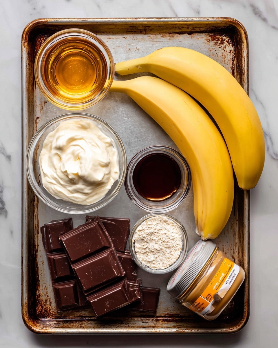 A close-up image shows several baking ingredients arranged on a tarnished baking tray placed on a white marbled surface. At the top right, two smooth, bright yellow bananas rest side by side. To the left of the bananas, a clear glass cup holds golden honey with a shiny, thick texture. Below the honey, a metal measuring cup is filled with thick, white Greek yogurt, its surface smooth with one little scoop mark. Next to it, on the bottom left, are pieces of dark chocolate arranged in two stacked bars with a rich, glossy finish. In the center, a small clear glass bowl contains dark amber vanilla extract. To the right of the vanilla, another metal measuring cup holds fine, white oat flour. At the bottom right, a jar of sunflower butter with an orange and white label and a yellow lid is tilted on its side, showing creamy, smooth texture inside. All items appear neatly placed and ready for use. Photo taken with an iphone --ar 4:5 --v 7