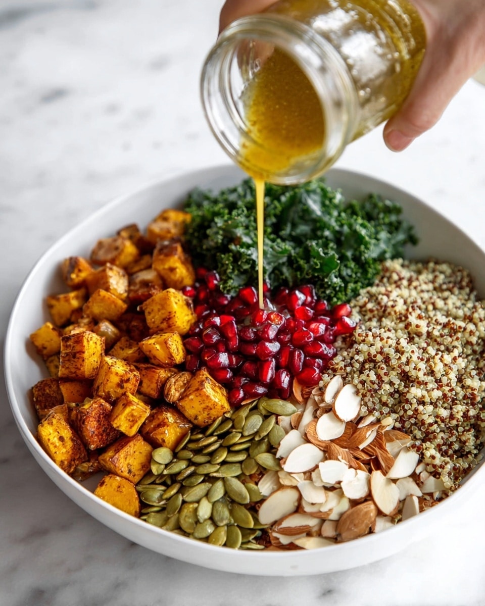 The image shows a white bowl filled with six distinct layers, neatly arranged side by side. Starting from the left, there are small, golden-brown roasted cubes, followed by bright red pomegranate seeds. Next to them is a pile of light green pumpkin seeds. A small bunch of dark green kale leaves sits next to the seeds. Then, there is a layer of cooked quinoa with white, brown, and red grains. On the far right are thin, light brown almond slices. A woman's hand is pouring a golden yellow dressing from a glass jar over the roasted cubes. The bowl is placed on a white marbled surface. photo taken with an iphone --ar 4:5 --v 7