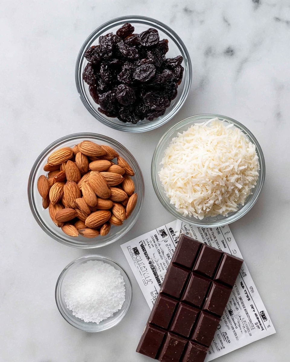 The image shows four clear glass bowls with different ingredients and a chocolate bar on a white marbled surface. The top bowl holds dark, wrinkled dried cherries, the bowl to the left contains smooth, light brown whole almonds. Below the almonds, there is a bowl filled with off-white shredded coconut flakes. A small bowl with coarse white salt is placed in the middle. On the lower right side, there is a dark brown chocolate bar with square segments resting partly on its white wrapper with black text. The setup is bright and clean with the bowls arranged neatly. photo taken with an iphone --ar 4:5 --v 7