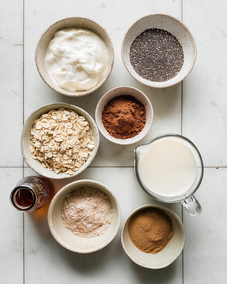 The image shows eight small white bowls and a clear glass jug placed on a white marbled surface arranged neatly in a square grid. Each bowl holds a different ingredient: one with white creamy yogurt in the top left; next to it a bowl filled with small black and white chia seeds; below the yogurt is a bowl with a round scoop of brown cocoa powder; next to cocoa powder is a bowl of rolled oats, light tan in color with rough texture; beside oats is a bowl with a small pile of brown cinnamon powder; below the oats is a bowl with light brown powder, likely flour or protein powder; at the bottom left is a small glass bottle with a dark liquid, likely vanilla extract; and finally, on the right side, a clear glass jug filled with white milk. The bowls and jug are spaced evenly on the clean white marbled surface. photo taken with an iphone --ar 4:5 --v 7