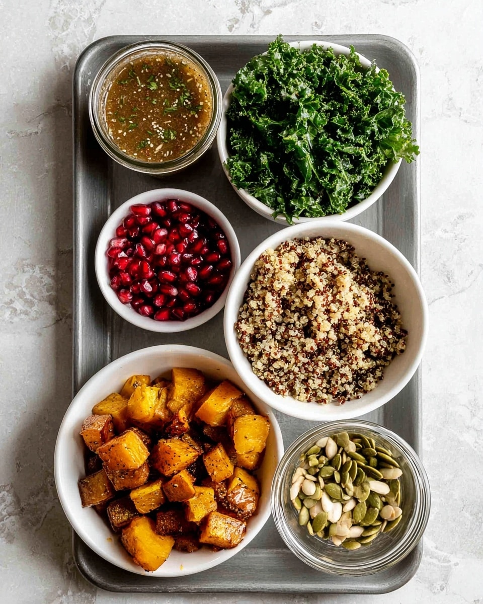 There is a grey metal tray on a white marbled surface holding several white bowls and a clear glass jar. The largest bowls include one at the top right filled with cooked quinoa that is light brown with dark specks, one at the left filled with bright green chopped kale with a leafy texture, and one below the quinoa filled with roasted golden-brown cubed squash with a slightly crispy look. Smaller white bowls contain green pumpkin seeds, sliced light beige almonds, and bright red glossy pomegranate seeds. The clear glass jar near the bottom left contains a light brown dressing with visible herbs. The photo taken with an iphone --ar 4:5 --v 7