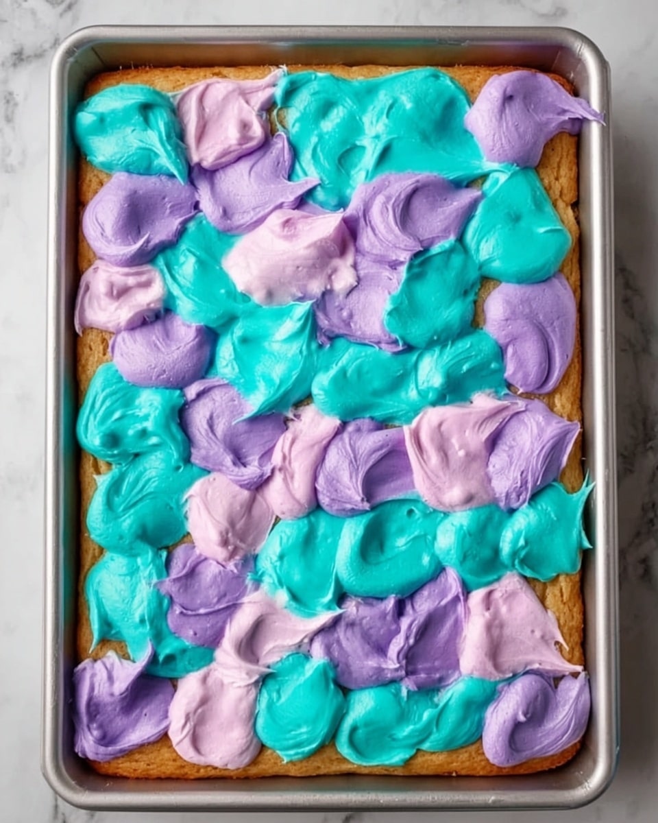 The image shows a rectangular baked cake with a golden-brown color as the base layer, placed inside a metal baking tray. On top of the cake, there are large dollops of frosting in two colors: bright turquoise and pastel purple. These dollops are spread unevenly but cover most of the surface of the cake, with the turquoises and purples alternating in a random pattern. The texture of the frosting looks soft and creamy with visible swirls and peaks. The whole tray is set on a white marbled surface. photo taken with an iphone --ar 4:5 --v 7