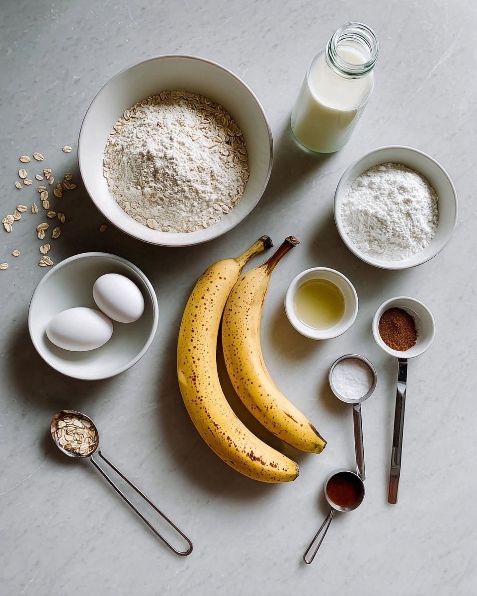 The image shows ingredients neatly laid out on a white marbled surface for a recipe. On the left, there is a white bowl filled with a powdery white substance, possibly flour or oats, with some oats scattered beside it. Below this bowl, there is a smaller white bowl holding two white eggs. In the center, two ripe yellow bananas with brown spots rest side by side. Above the bananas, there is a clear bottle filled with a white liquid, likely milk or a milk substitute. To the right of the bottle is a white bowl containing a white powder, perhaps baking soda and baking powder. Next to this bowl, two silver measuring spoons contain a dark brown spice, such as cinnamon, and a white powder, probably salt. Below these, another white bowl holds a clear liquid, likely oil or lemon juice. At the bottom edge, a silver measuring spoon with a brown liquid, possibly vanilla extract, completes the arrangement. The setup is clean and minimalistic, with a soft natural light, photo taken with an iphone --ar 4:5 --v 7