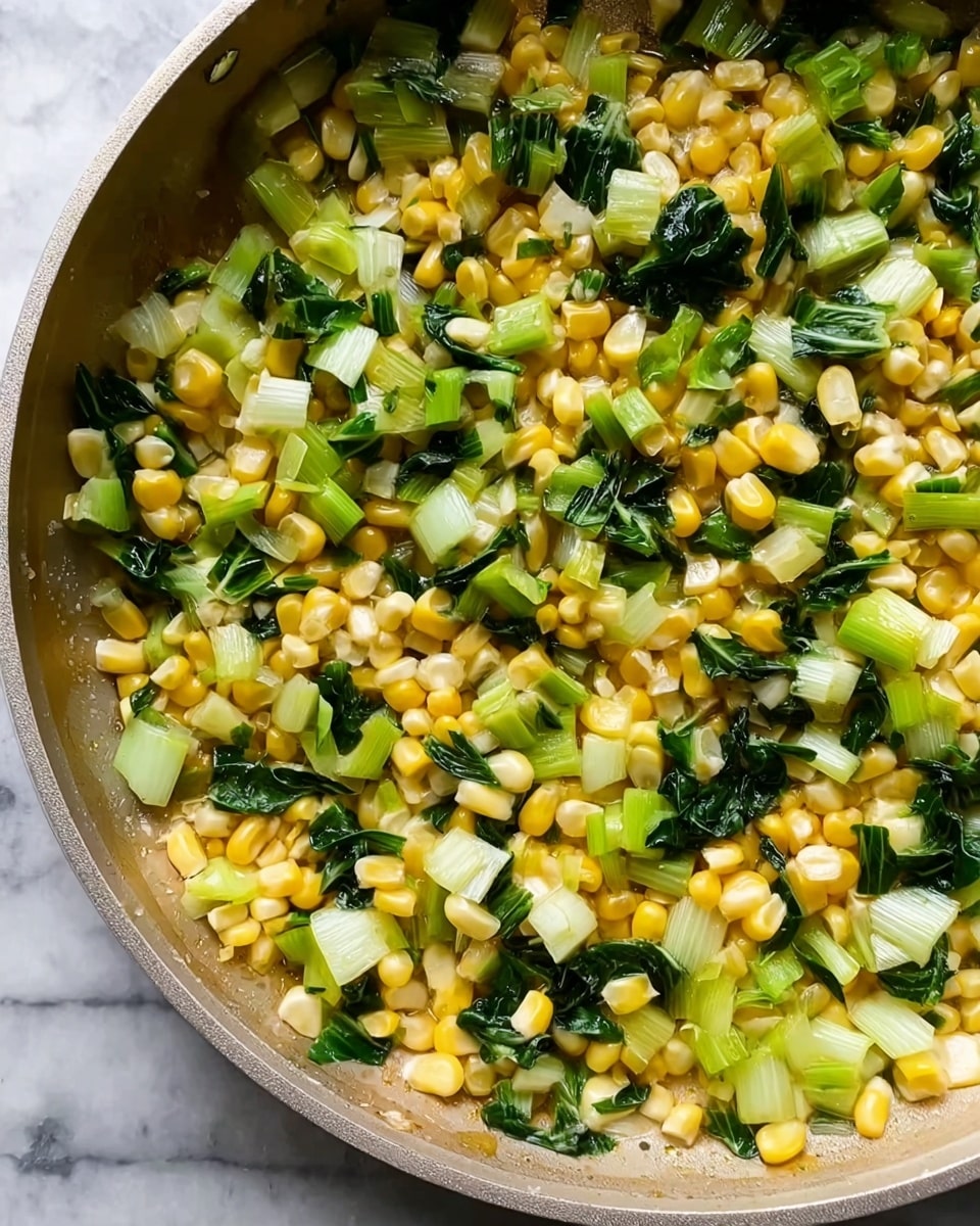 A close-up top view of a light-colored pan filled with cooked yellow corn kernels mixed with chopped light green bok choy stems and dark green leafy parts spread evenly throughout. The vegetables look slightly shiny as they are cooked, with smooth corn and crisp-looking greens, all sitting on a white marbled surface. photo taken with an iphone --ar 4:5 --v 7