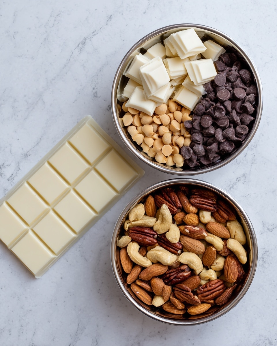 The image shows two shiny metal bowls placed on a white marbled surface. The bowl on the left contains three main layers: creamy white almond bark squares on top, small round peanut butter chips light tan in color, and a layer of dark brown chocolate chips in the front. The bowl on the right is filled with mixed nuts, including a variety of light brown peanuts, golden cashews, darker brown almonds, and pecans, all mixed together. Below the bowls lies a white baking chocolate bar partially unwrapped from silver foil, displaying a smooth, creamy white surface divided into six rectangular pieces. photo taken with an iphone --ar 4:5 --v 7