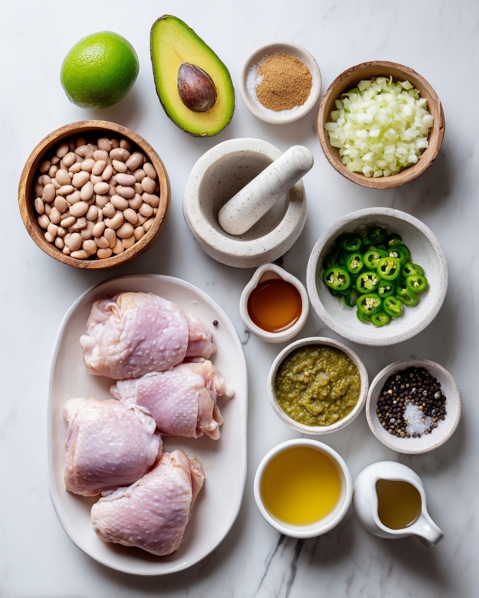 The image shows various cooking ingredients arranged on a white marbled surface. At the top left, there is a whole lime next to a half avocado with its seed in place. Near these, a small wooden bowl holds cumin powder, and to its right, a small white bowl contains coarse kosher salt. Below the salt, a small white bowl holds minced garlic. In the middle, a wooden bowl is filled with chopped green chilies. Below the chilies, a white mortar with a pestle holds black peppercorns. To the right, a larger white bowl contains finely chopped yellow onion. Below these, an oval white plate has four raw chicken thighs with skin on, pink with fat visible around the edges. To the left of the chicken, a white bowl contains pinto beans in liquid. Above it, a small white cup has golden olive oil. Below the beans, a white small pitcher contains reddish chicken stock. To the bottom right, a white bowl holds light green tomatillo salsa with a coarse texture. All items are clear and well-lit, with a natural overhead light. Photo taken with an iphone --ar 4:5 --v 7